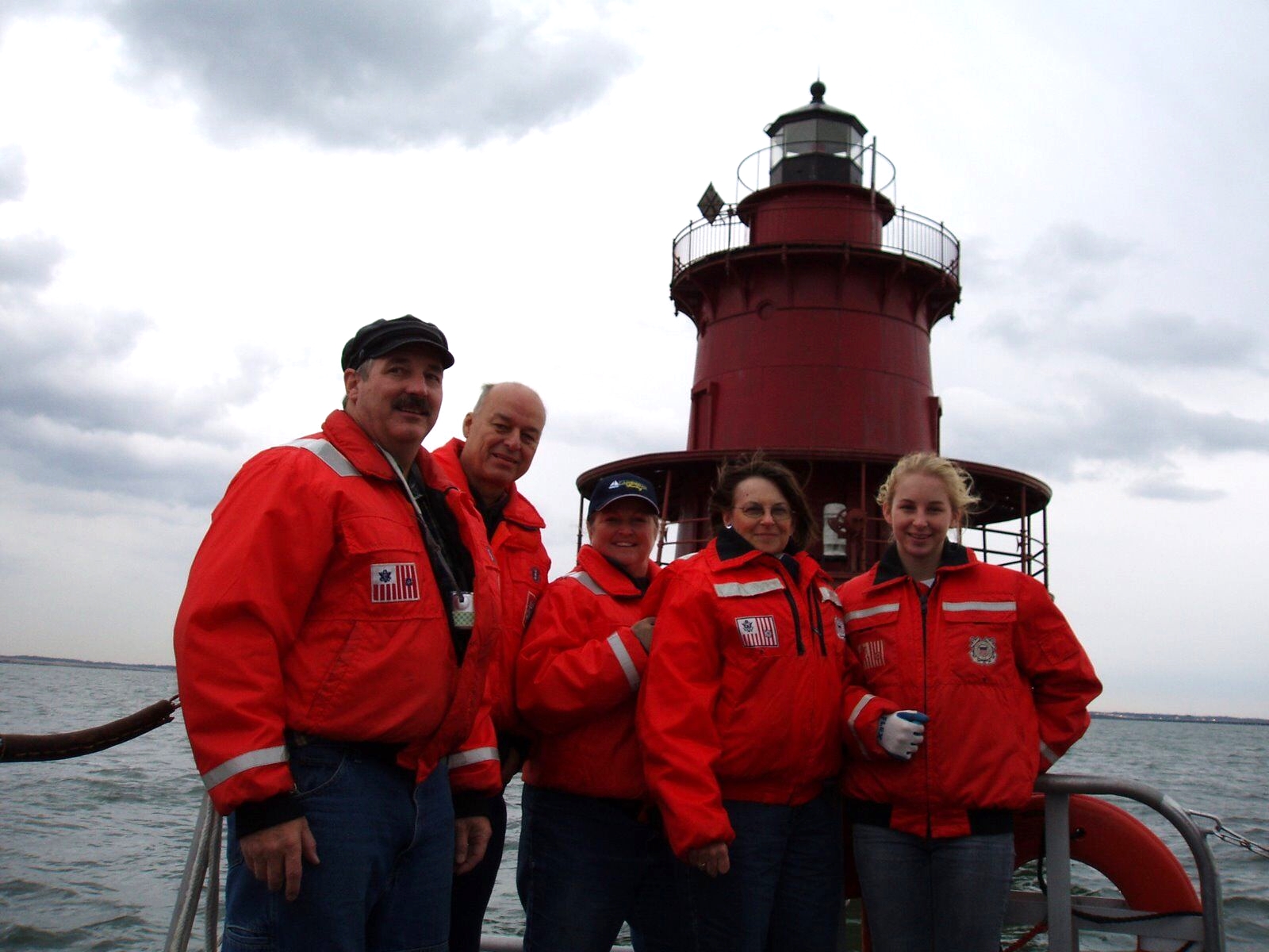 Private ownership of Middle Ground Lighthouse on a boat, with water and a cloudy sky in the background.