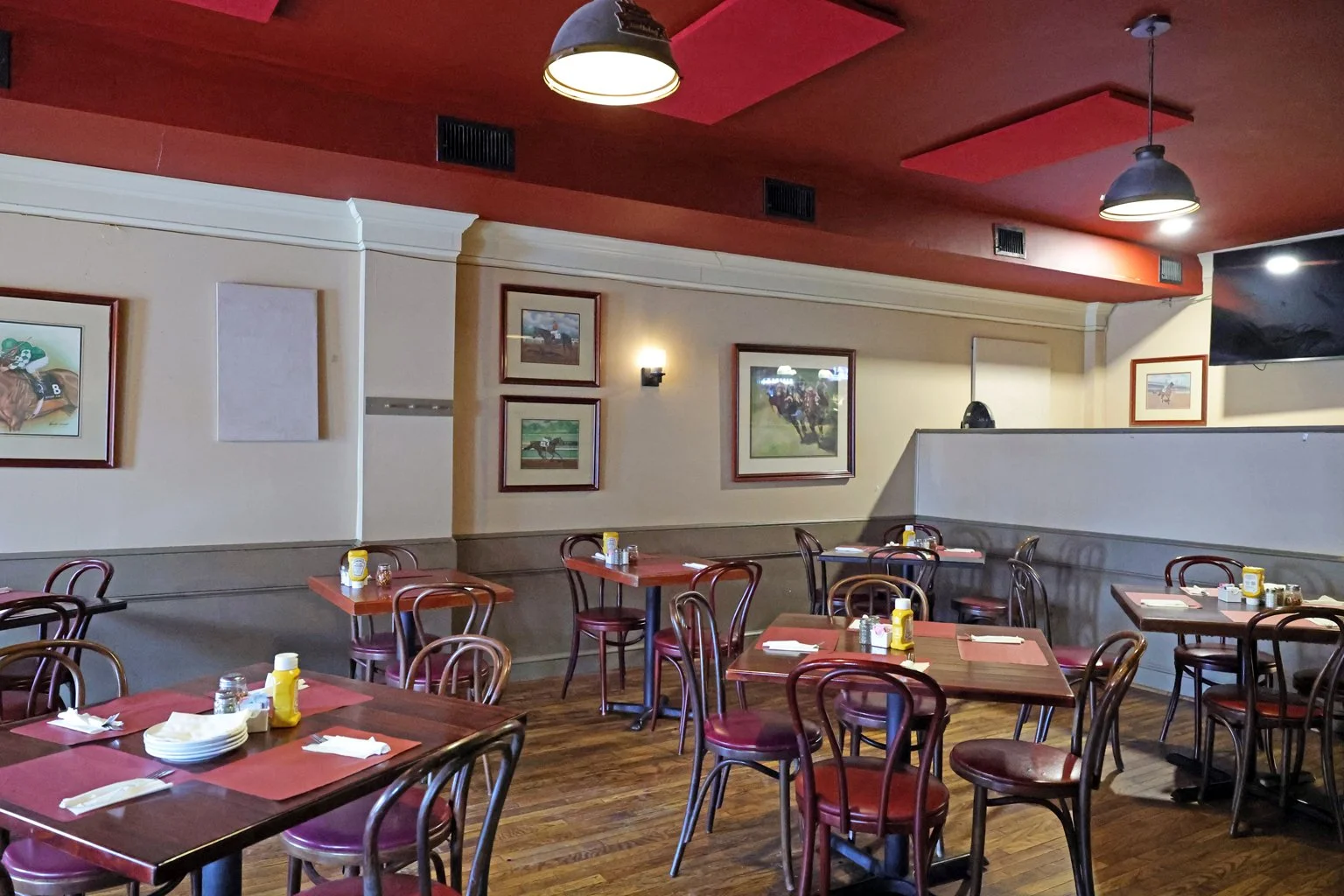 Restaurant dining area with  tables and chairs, as well as framed pictures on the walls.