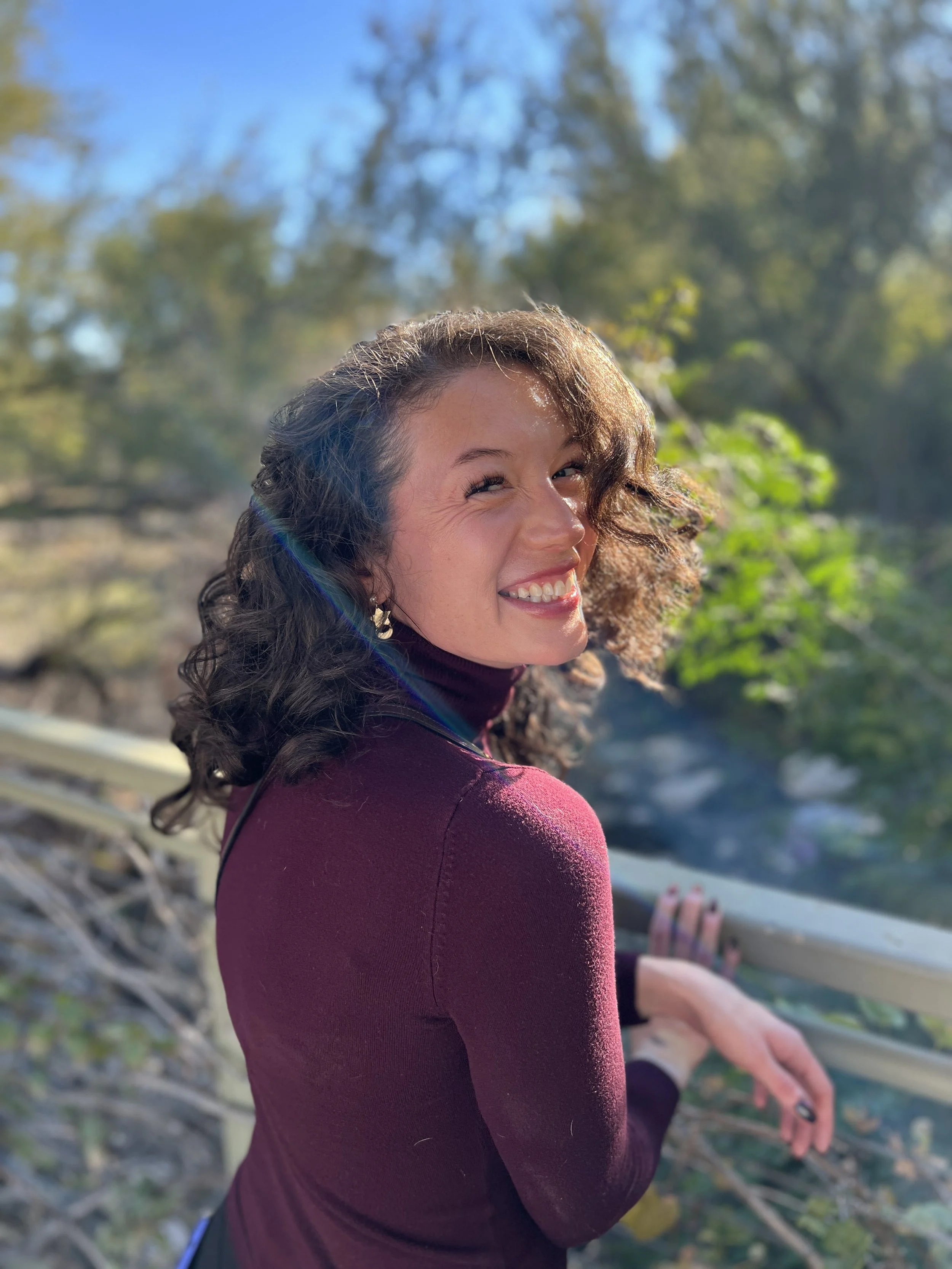 Camalot Todd, founder of Camalot Co, smiling at Springs Preserve in Las Vegas, wearing a maroon turtleneck.