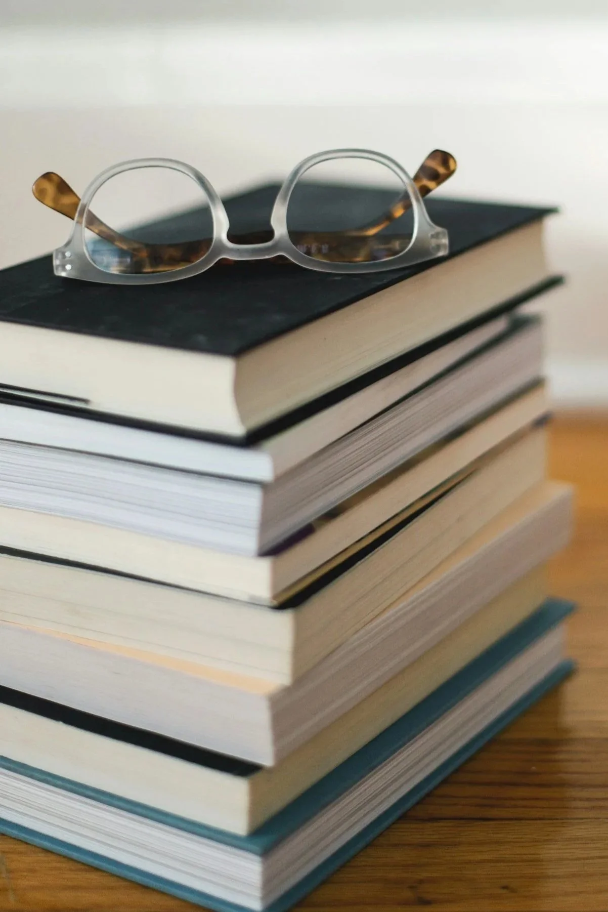 Stack of books with a pair of reading glasses on top.