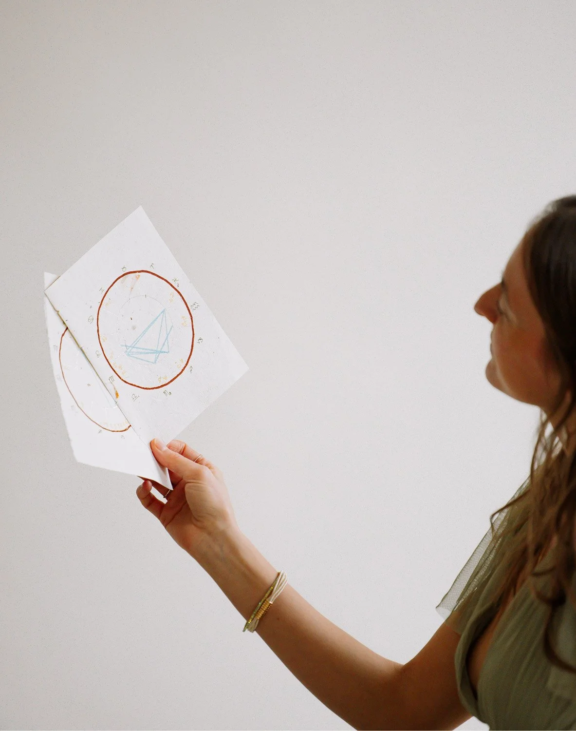Rachelle Hicks, astrologer, holding and interpreting birth chart drawings as part of an astrology journey