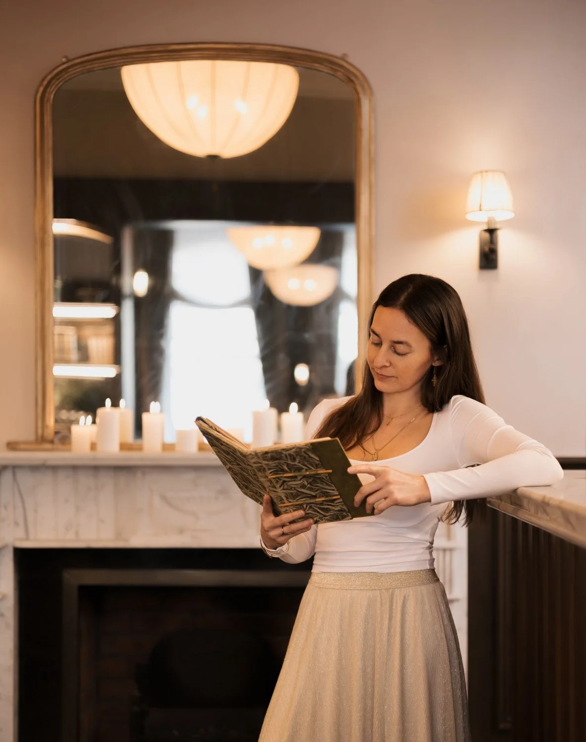 Rachelle Hicks, online astrologer, reading and studying in a softly lit interior space
