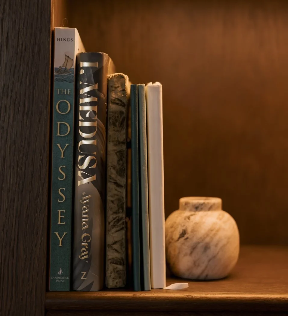 Collection of astrology and mythology books on a shelf in a warm, softly lit setting