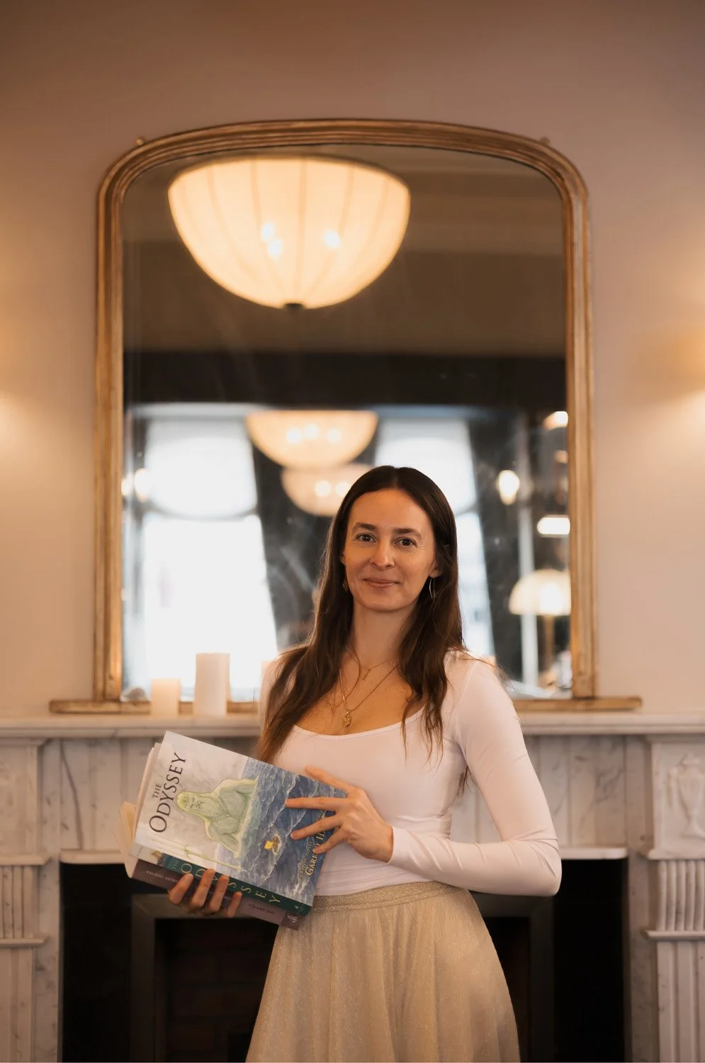 Rachelle Hicks, astrologer, holding a mythology book as part of an astrology journey
