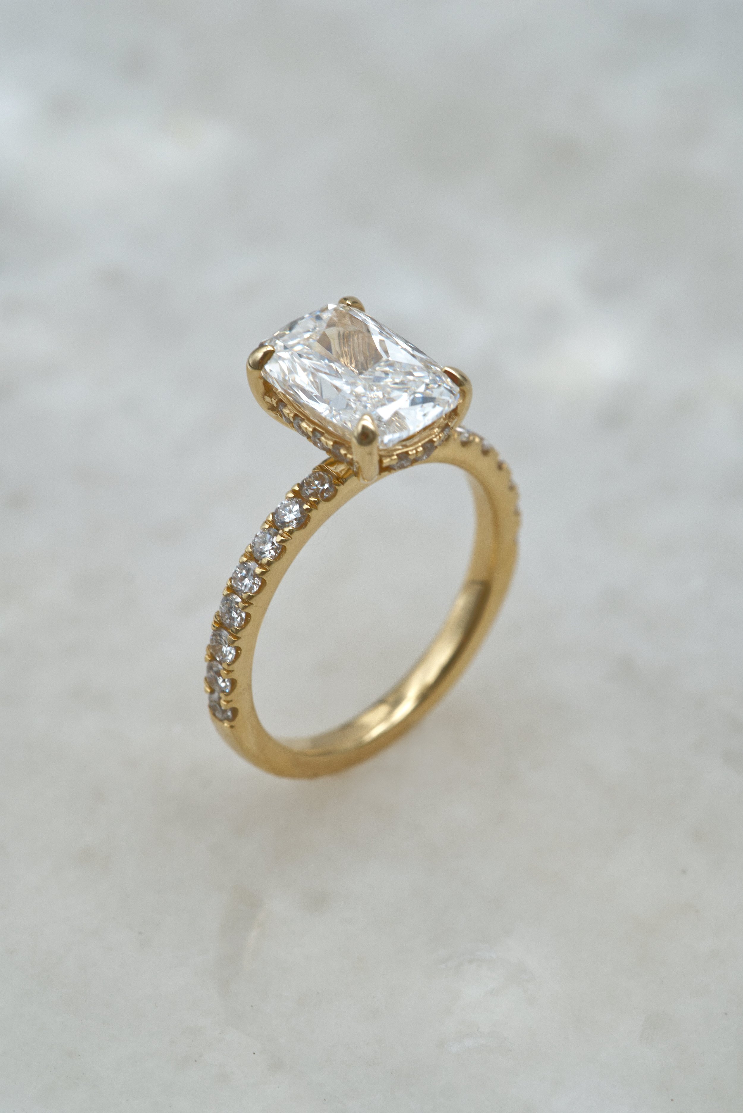 Gold ring with an elongated cushion gemstone and pavé band with small diamonds.