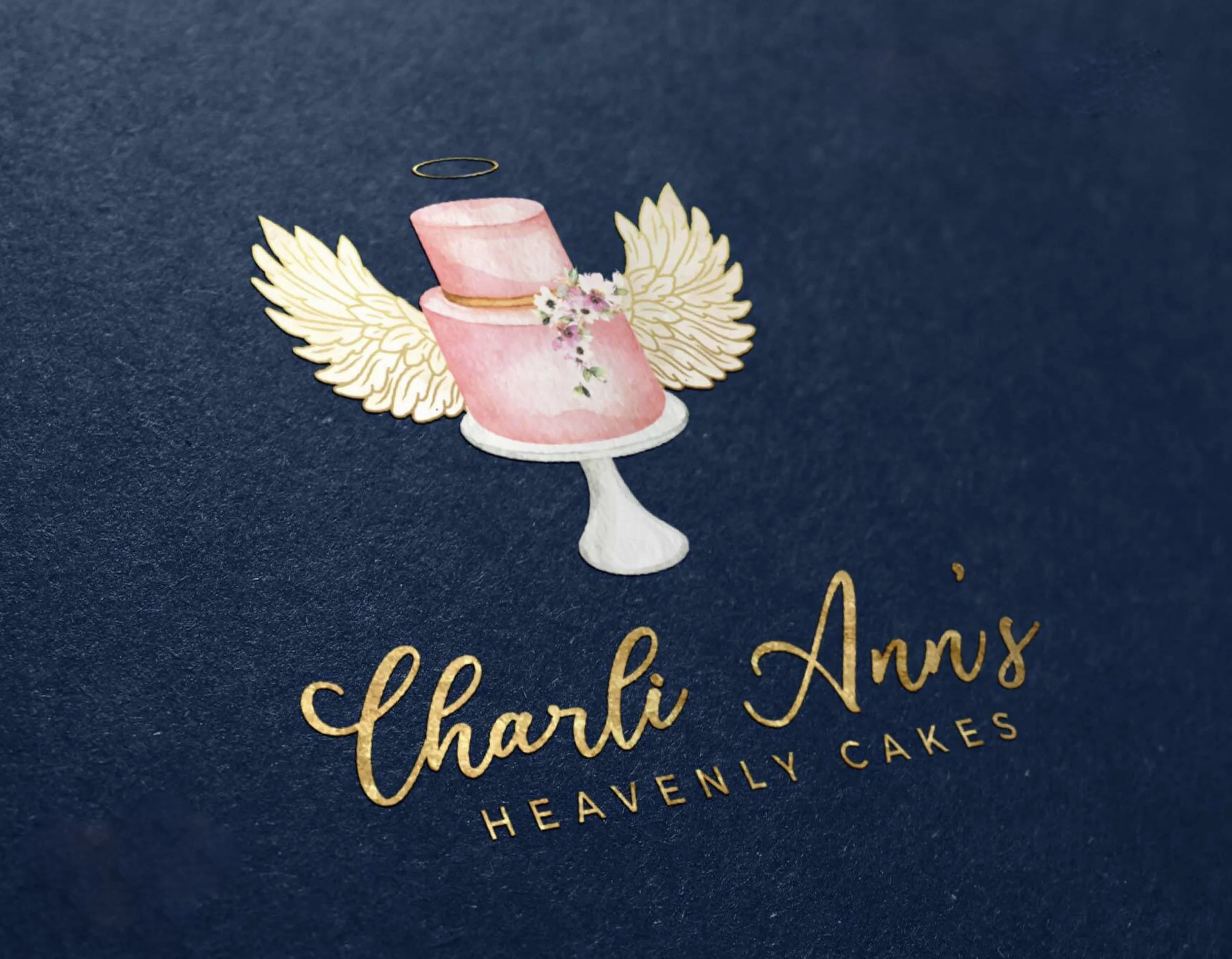 Decorative cake topper featuring a pink, two-tier cake with floral decorations, golden wings, and a halo, set against dark blue background.