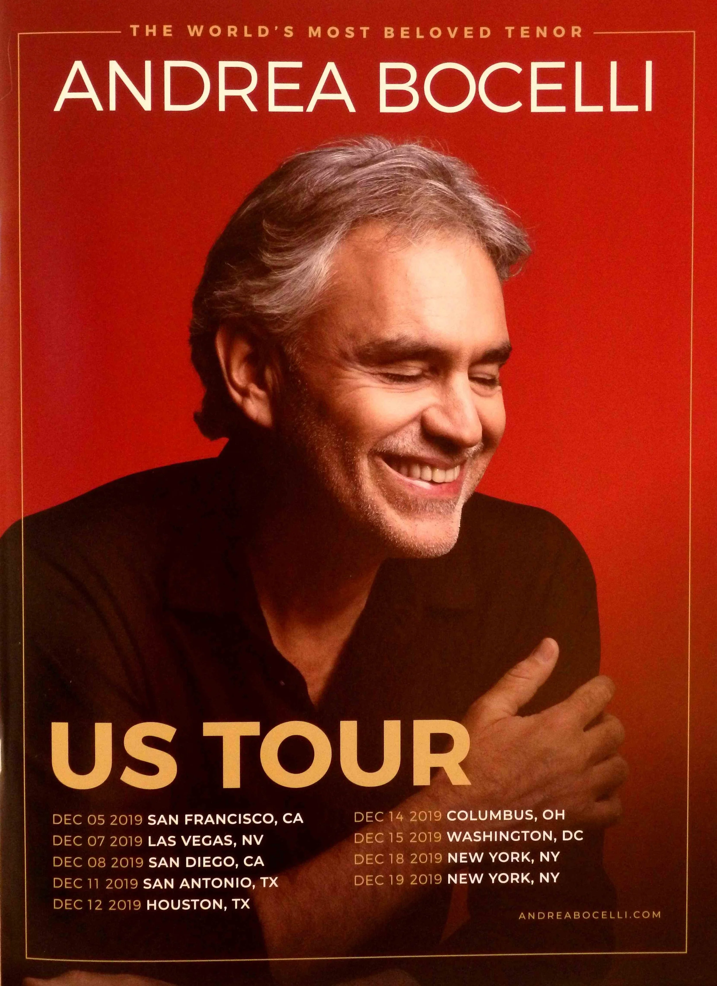 Poster advertising Andrea Bocelli's U.S. tour, featuring a smiling Andrea Bocelli with gray hair, wearing a black shirt, set against a red background, with tour dates and locations listed.