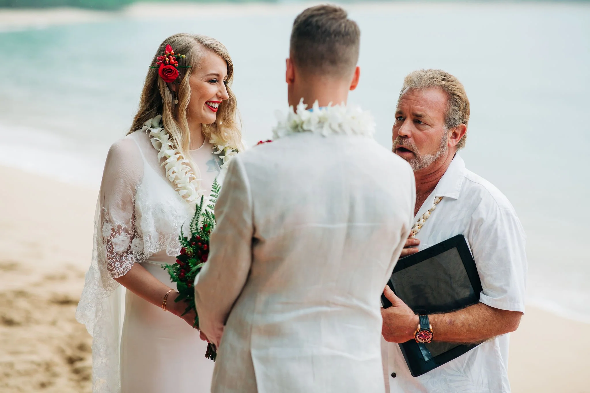 A couple getting married on the beach with an officiant during a wedding ceremony.