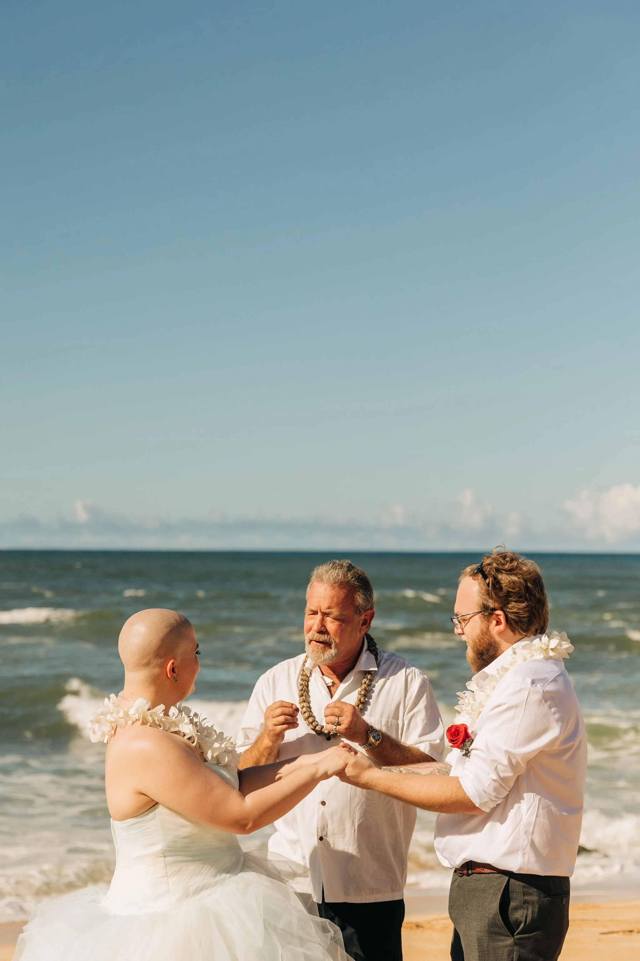 A couple getting married on the beach with officiant during daytime.