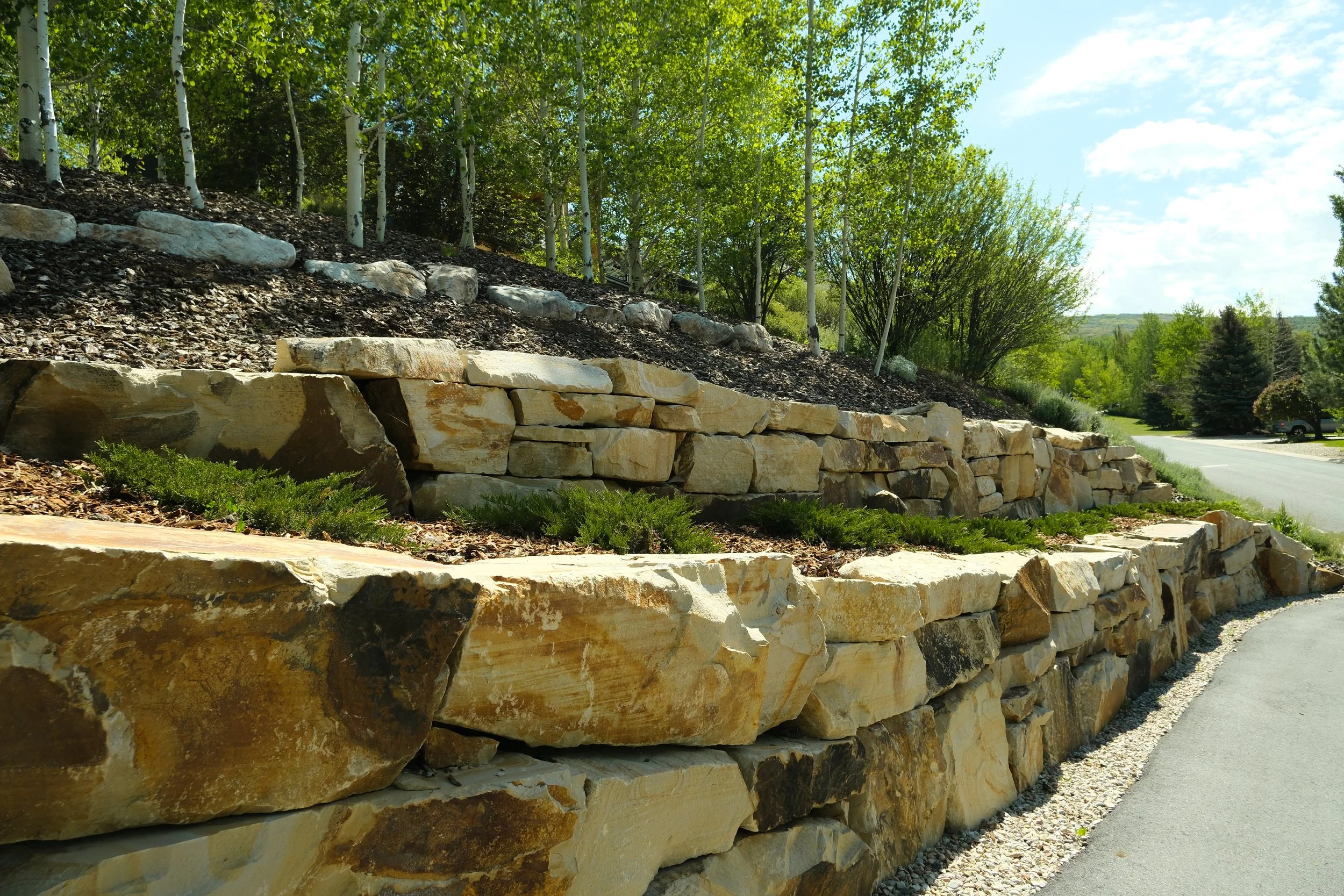 Stone patio by a small pond with green grass and trees in the background.