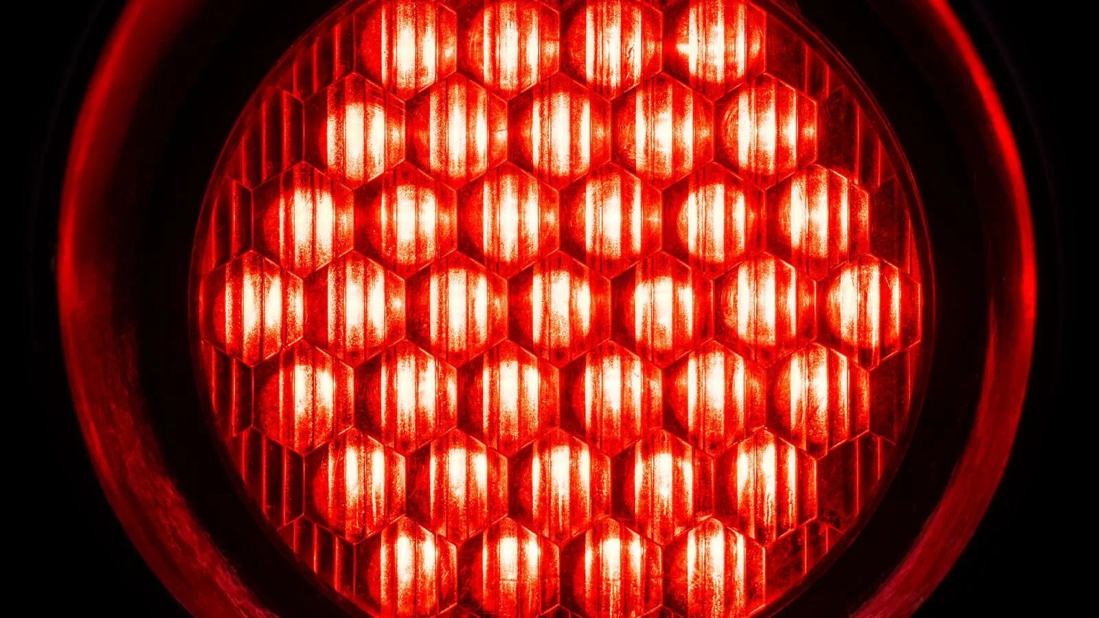 Close-up of a red illuminated honeycomb-patterned light fixture with a black outer frame.