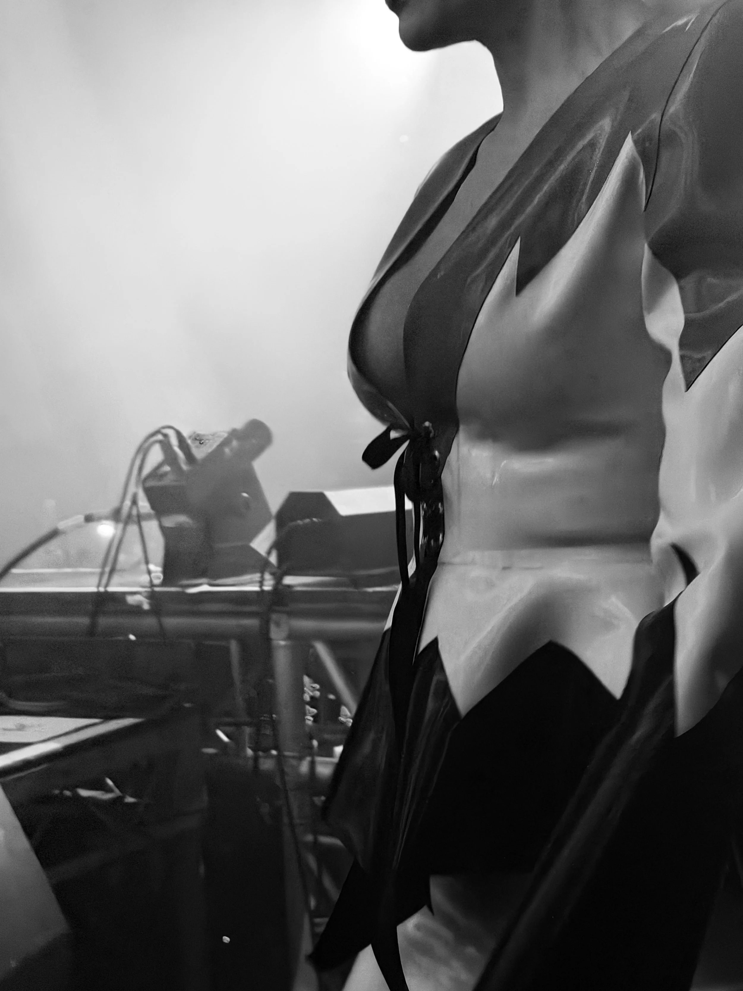 Close-up of a mannequin wearing a uniform, with a blurred electronic device and wires in the background.