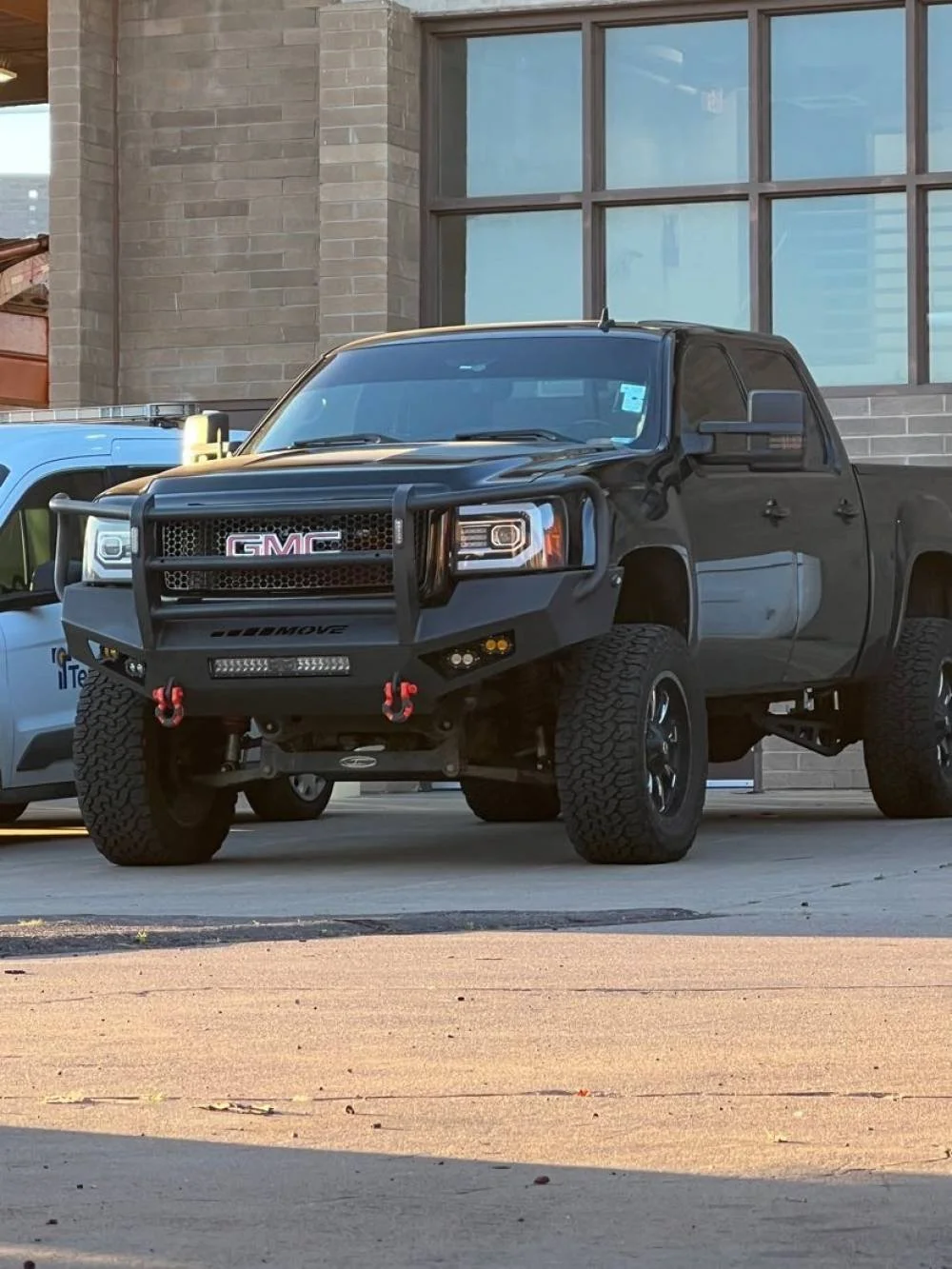 GMC truck with custom steel front bumper parked in front of modern building