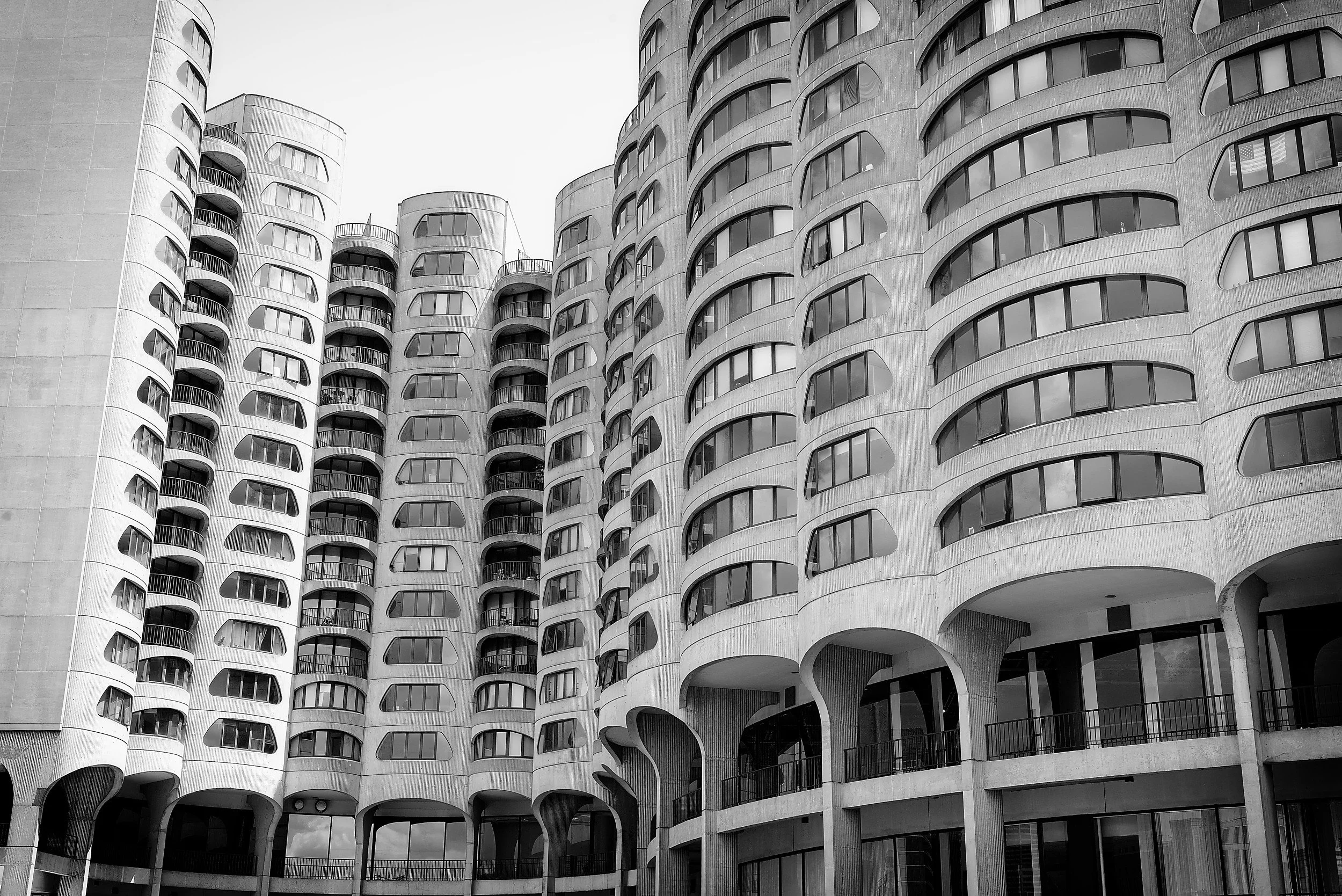 Black and white photo of a modern high-rise apartment building with curved balconies and large windows
