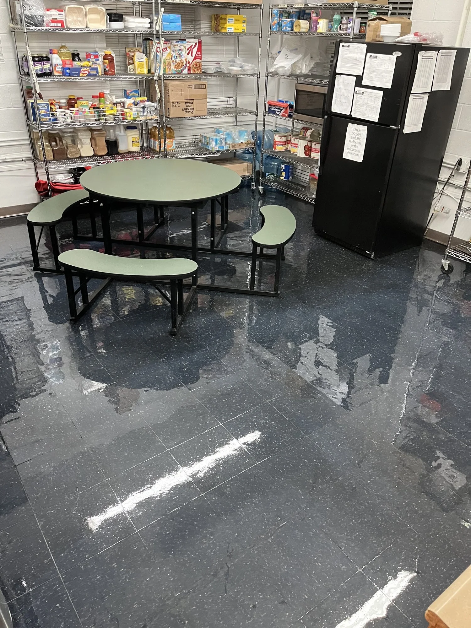 The same day care lunchroom floor after stripping and waxing: the tile is glossy and reflects the overhead lights and furniture.