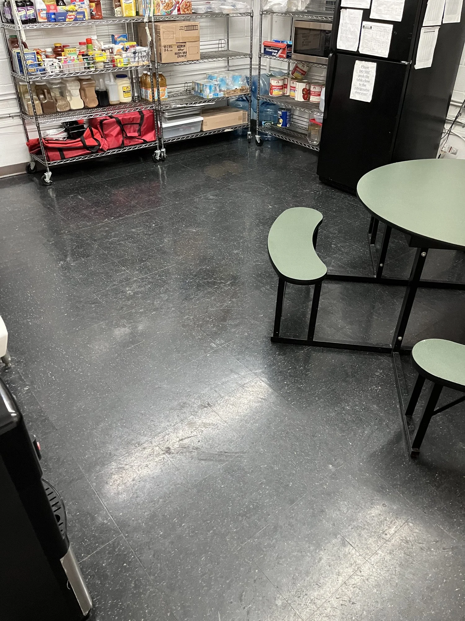 Day care lunchroom floor before restoration: dark VCT tile looking hazy and dull, with visible scuff marks and no reflection.