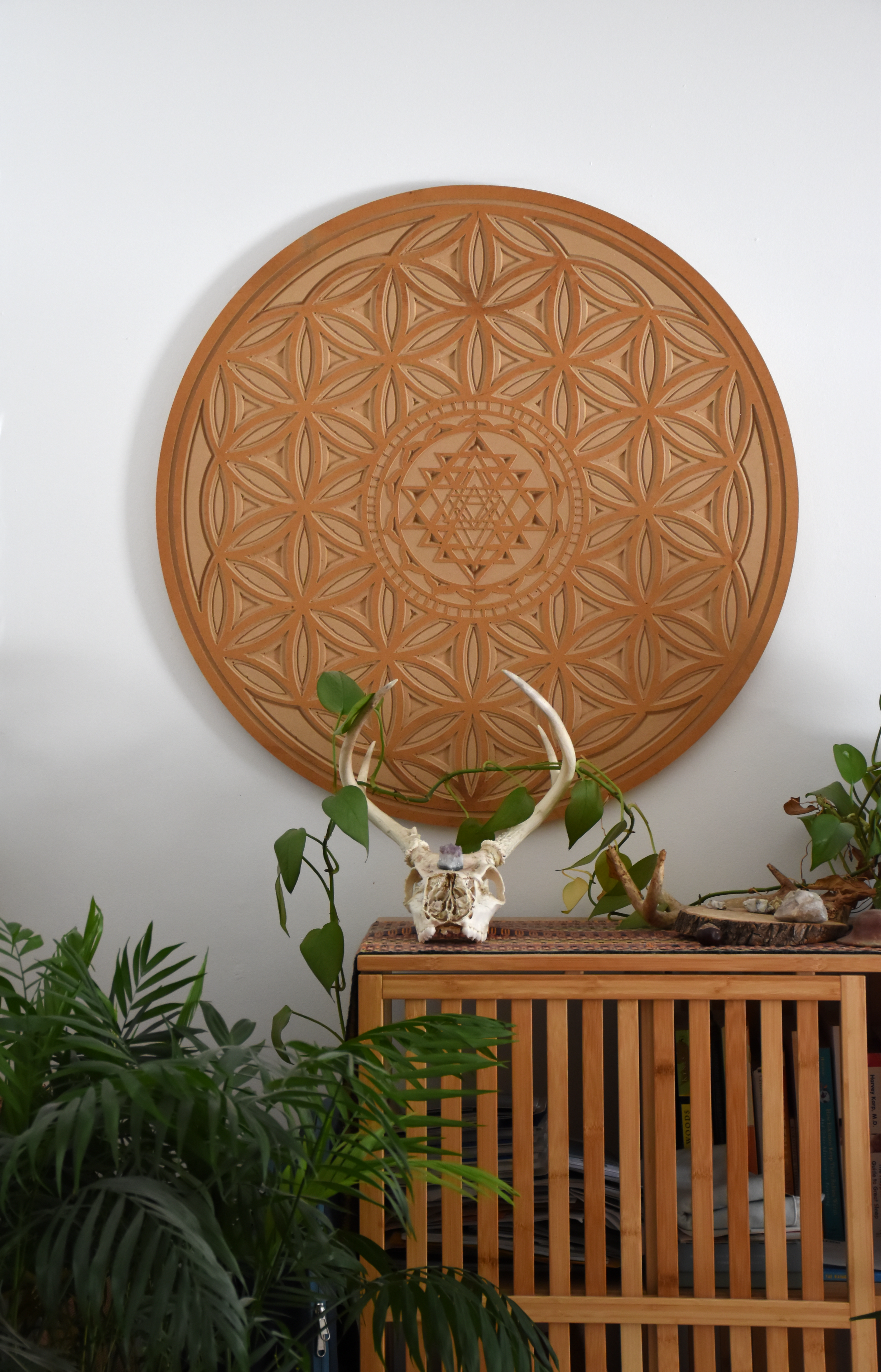Decorative wooden wall art with geometric patterns, a skull with antlers and plants on a wooden table.