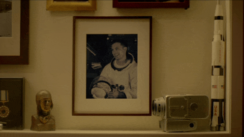 Decorative shelf with framed photograph of a woman, a small sculpture, a vintage camera, and a rocket-shaped object.
