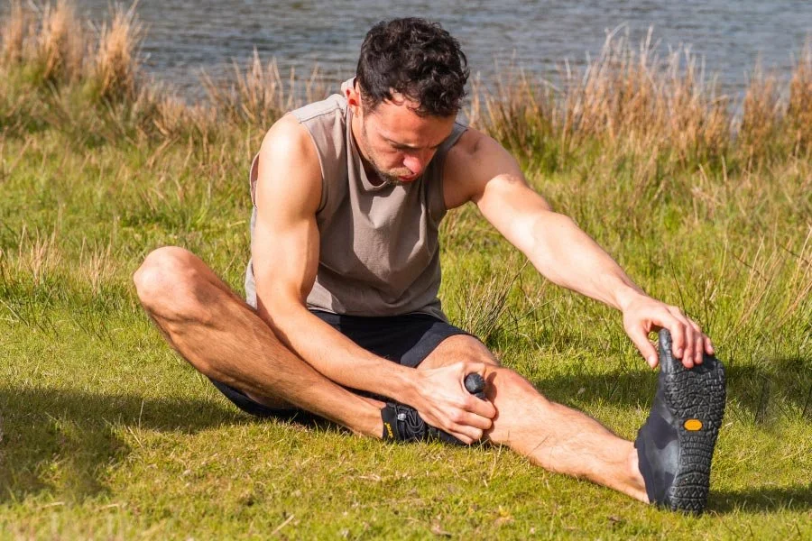 Personal Trainer stretching outdoors on grass by a lake