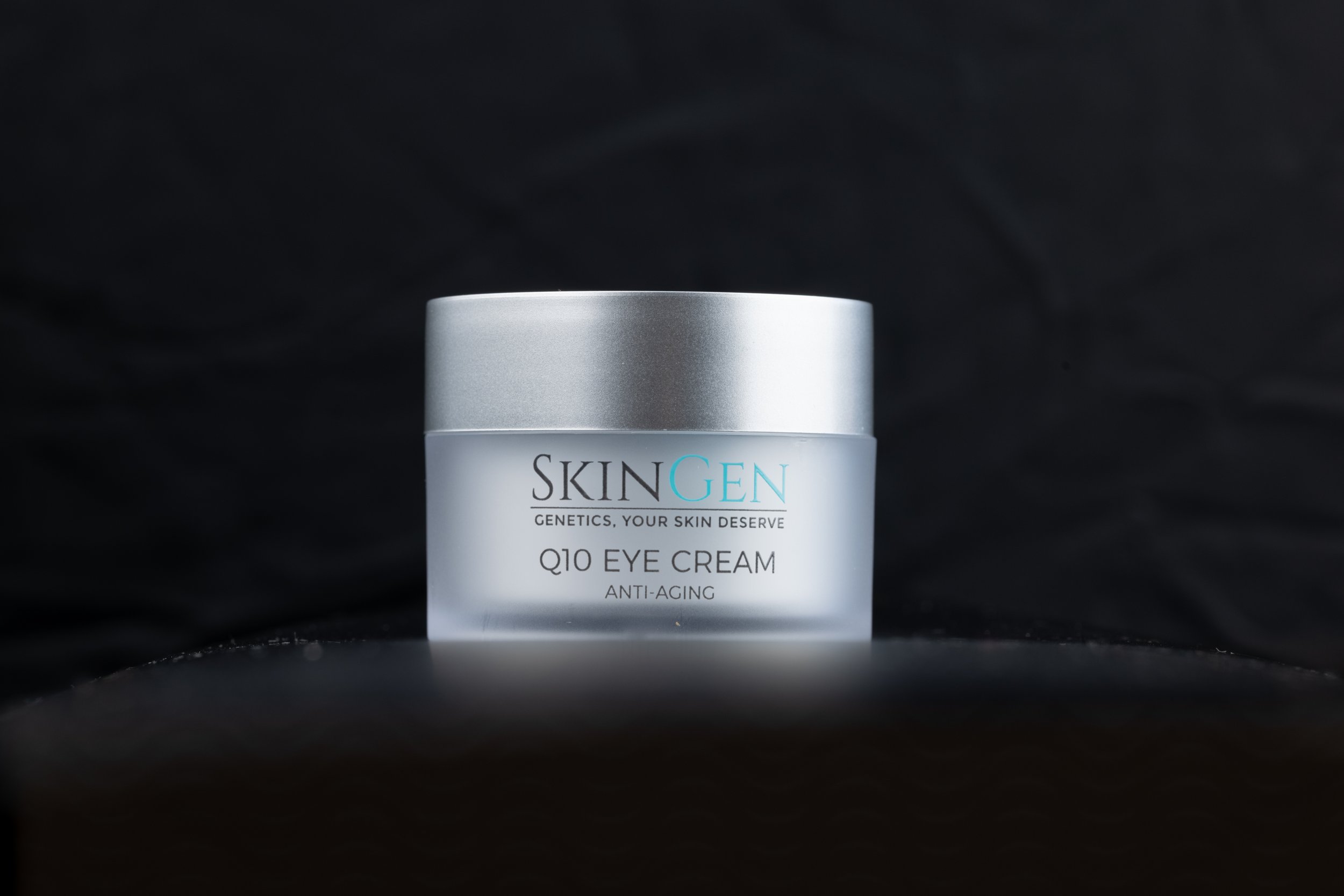 A container of SKINGEN Q10 Eye Cream Anti-Aging on a black background.