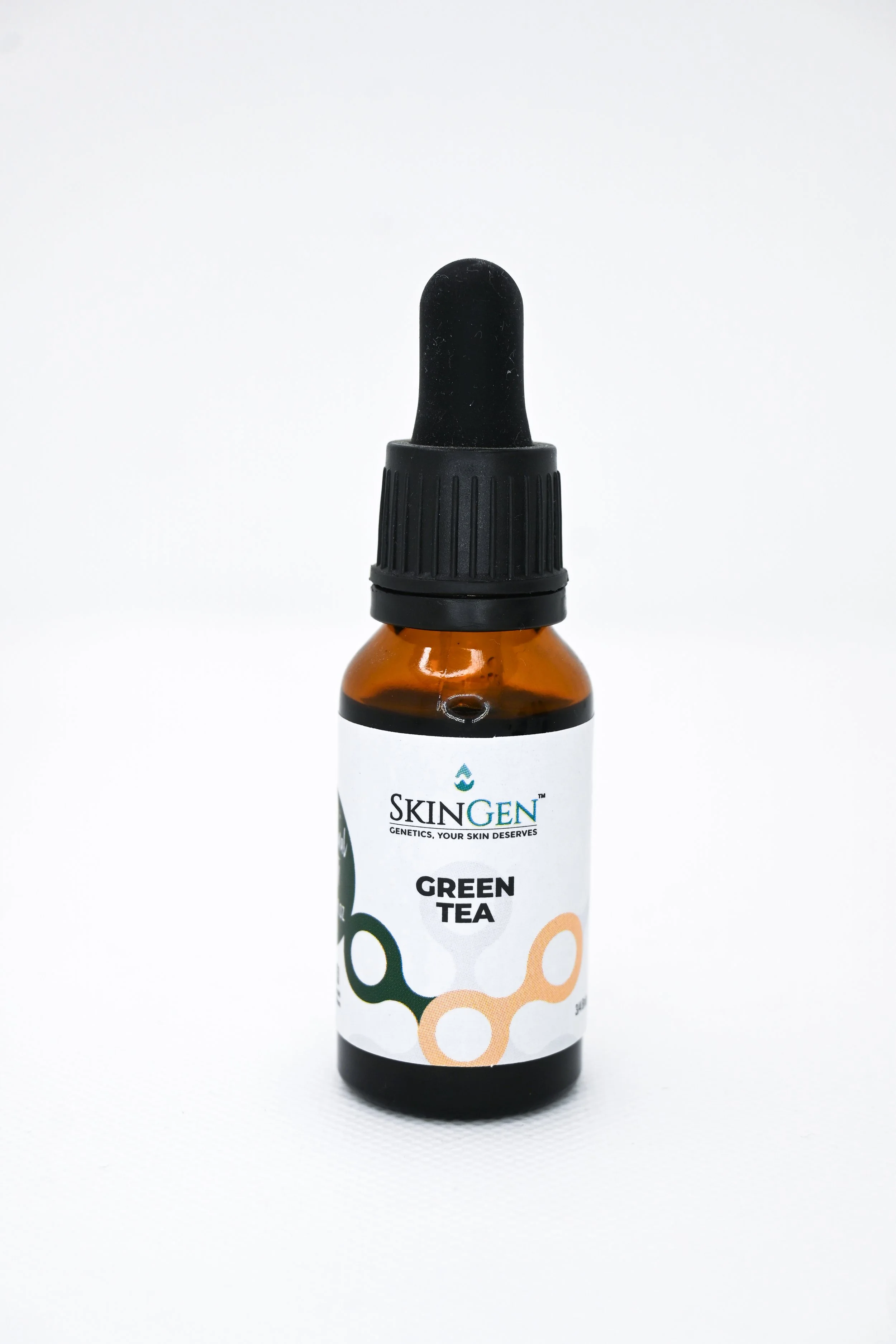 A small amber glass bottle of SkinGen green tea skincare serum with a black dropper cap, placed on a white surface.