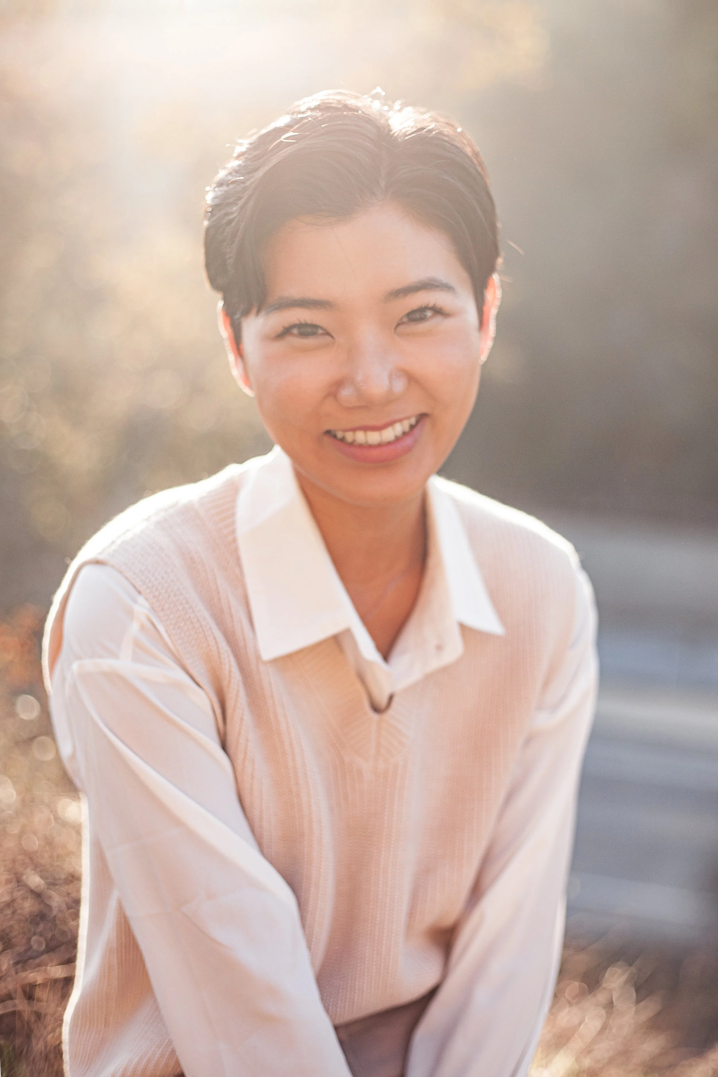 Dr. Seohyun Joo with short hair, smiling warmly in a serene forest. A welcoming image for your initial consultation, inviting you to explore your inner world with courage. 숲속에서 환하게 웃고 있는 숏컷의 주서현 박사. 내면을 마주할 용기를 환영하는 따뜻한 상담 신청 안내 사진입니다.