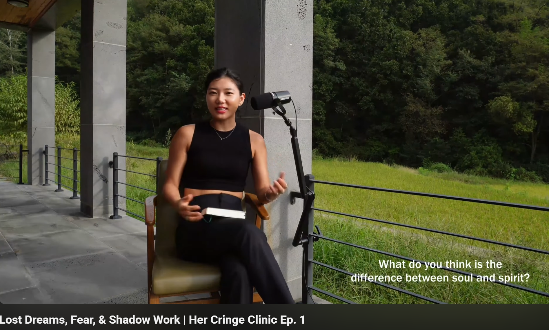 Dr. Seohyun Joo sitting outdoors in a forest, discussing "The difference between Soul and Spirit" for Her Cringe Clinic. A female psychologist with short hair speaking into a microphone. 숲속에서 '혼(Soul)과 영(Spirit)의 차이'에 대해 질문하는 주서현 박사의 유튜브 영상 스크린샷.
