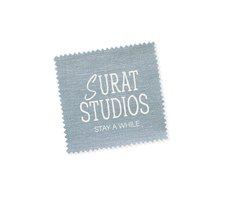 A fabric label with the text "Surat Studios Stay A While"