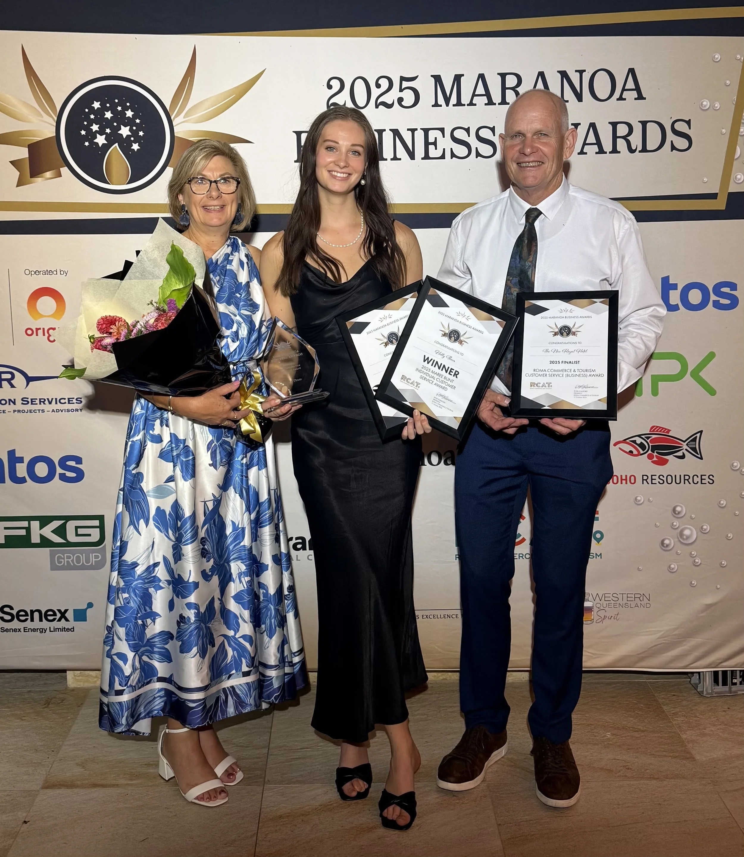 The founders standing together at an awards ceremony. They are holding awards and framed certificates, smiling for the photo. The background displays a banner with the text "2025 Business Awards".