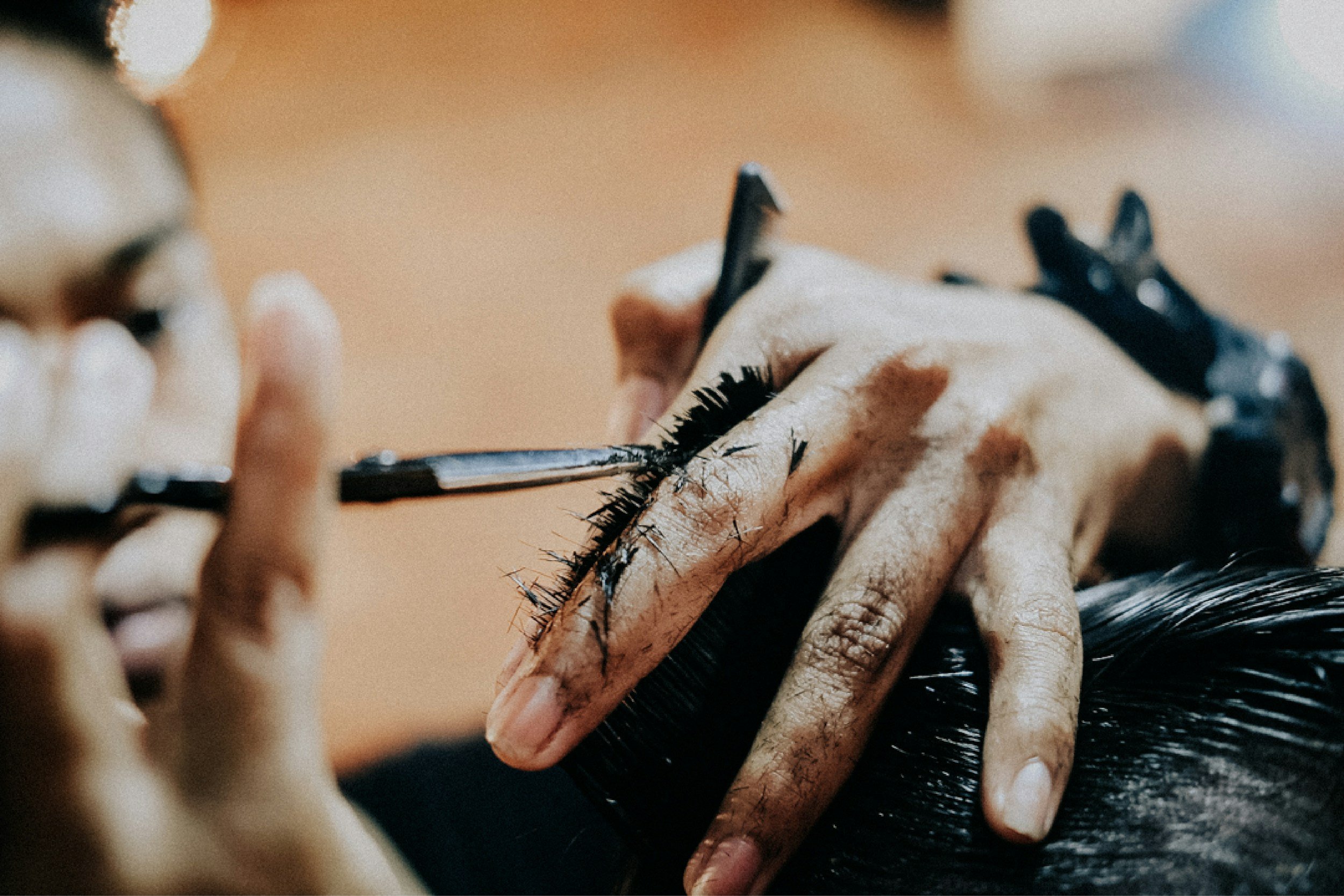 A person receiving a makeup application, with close-up focus on their eye and hand as makeup artist applies eyeshadow or eyeliner.