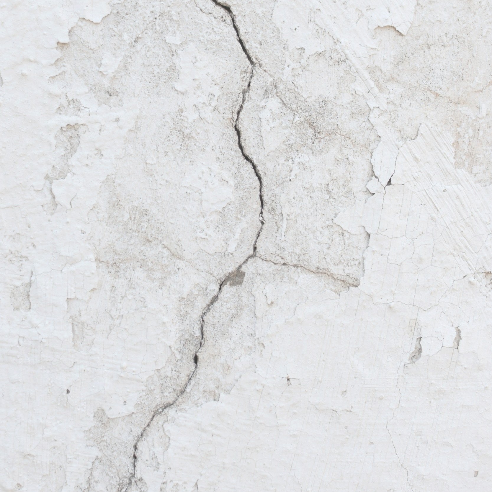 Close-up of a white, cracked and peeling wall surface.