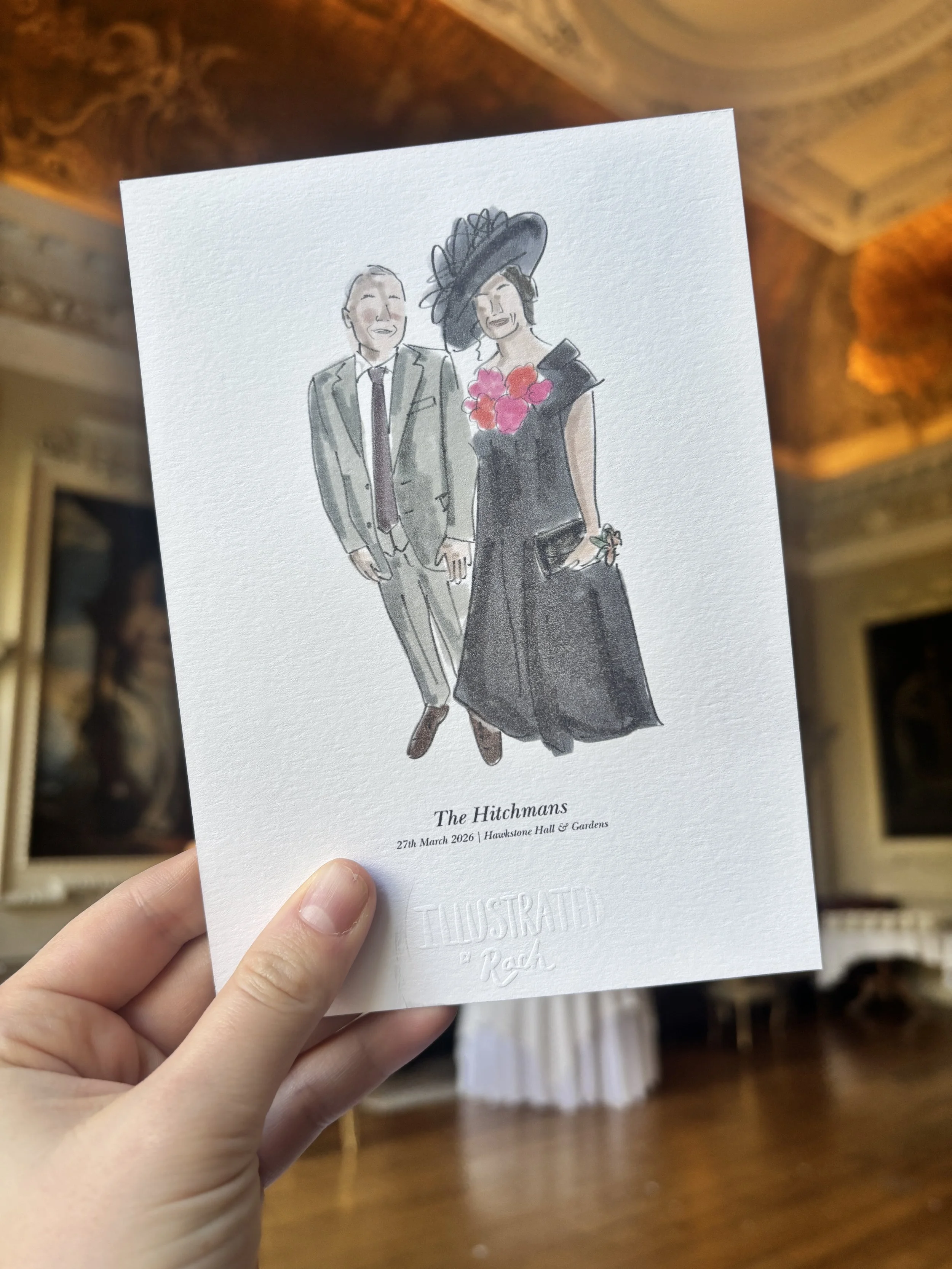 A hand holding a printed illustration of an elderly man and woman dressed in formal attire, with the woman wearing a large hat and flowers, festival details and date below.