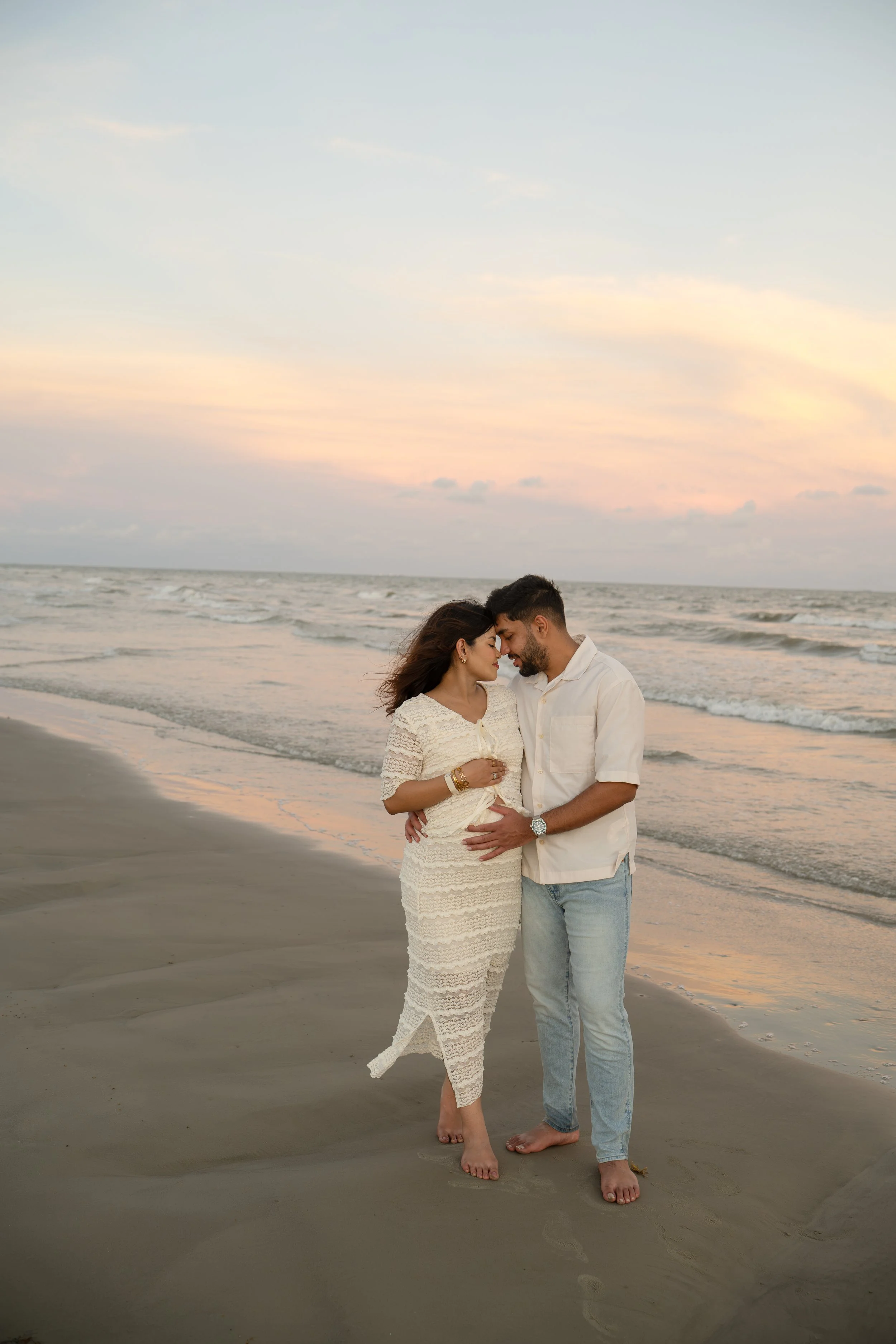 houston couple embracing at the beach at sunset during maternity photos galveston