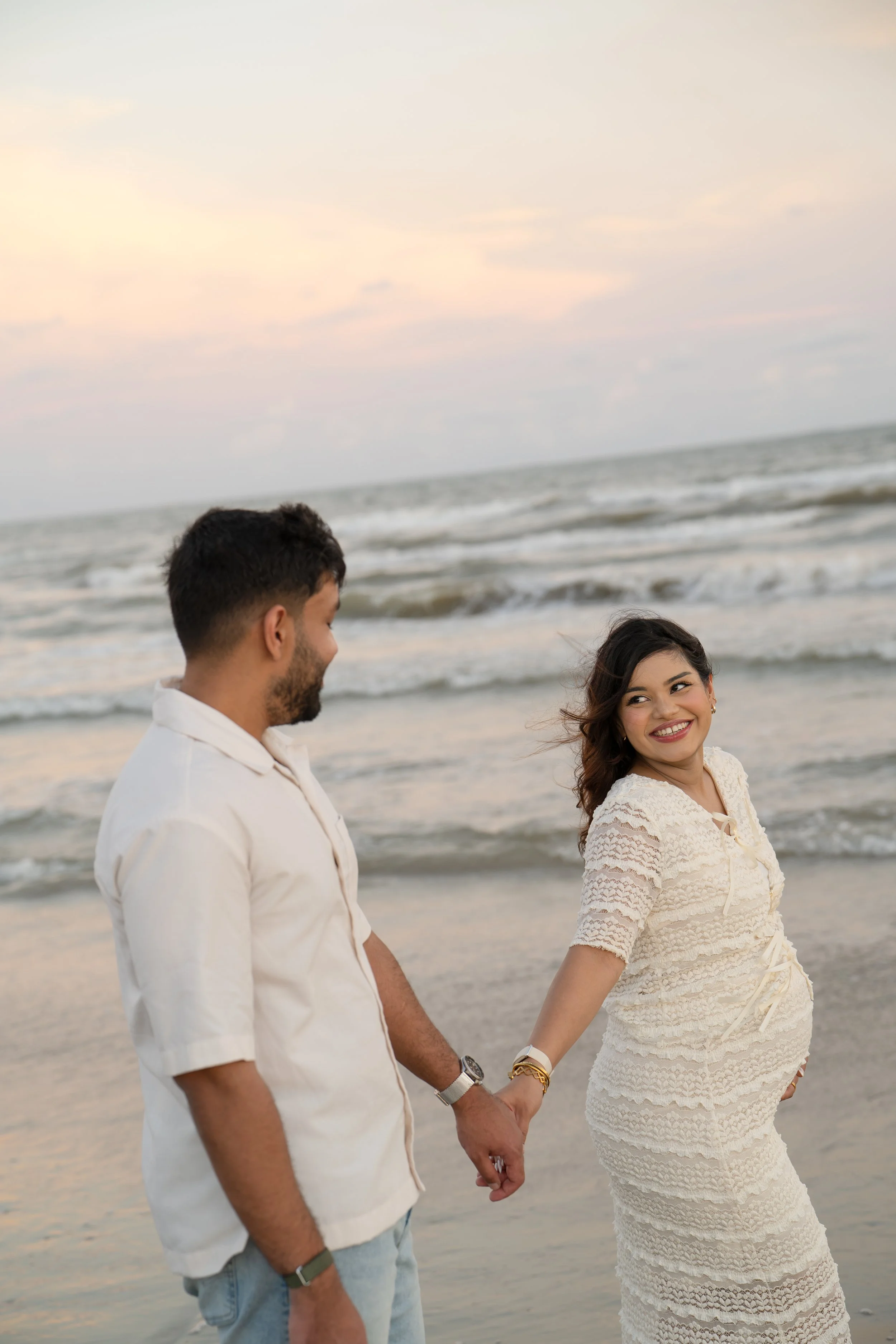 houston couple smiling at the beach with mom's pregnant belly on display