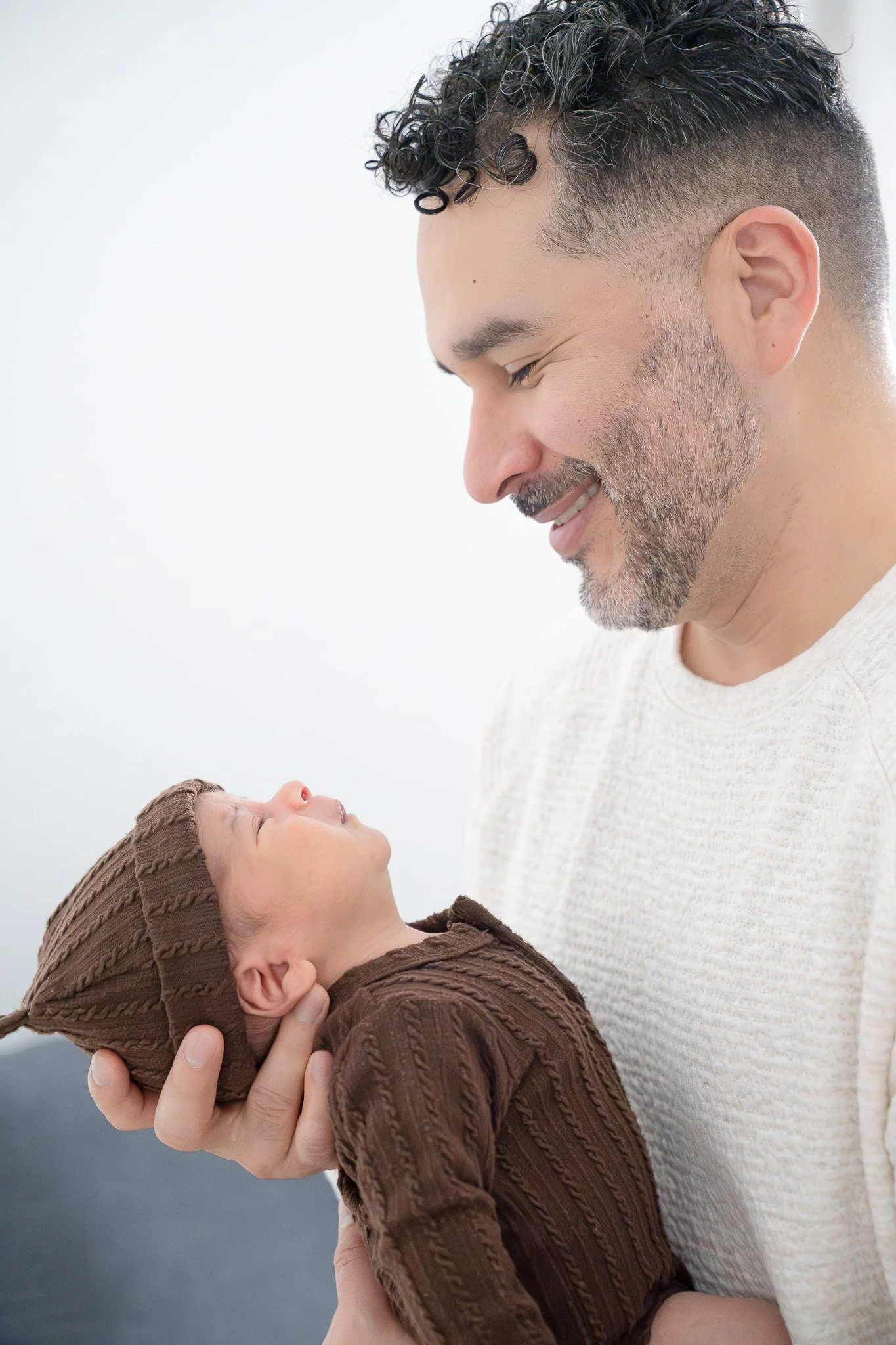 dad holding newborn and smiling at home