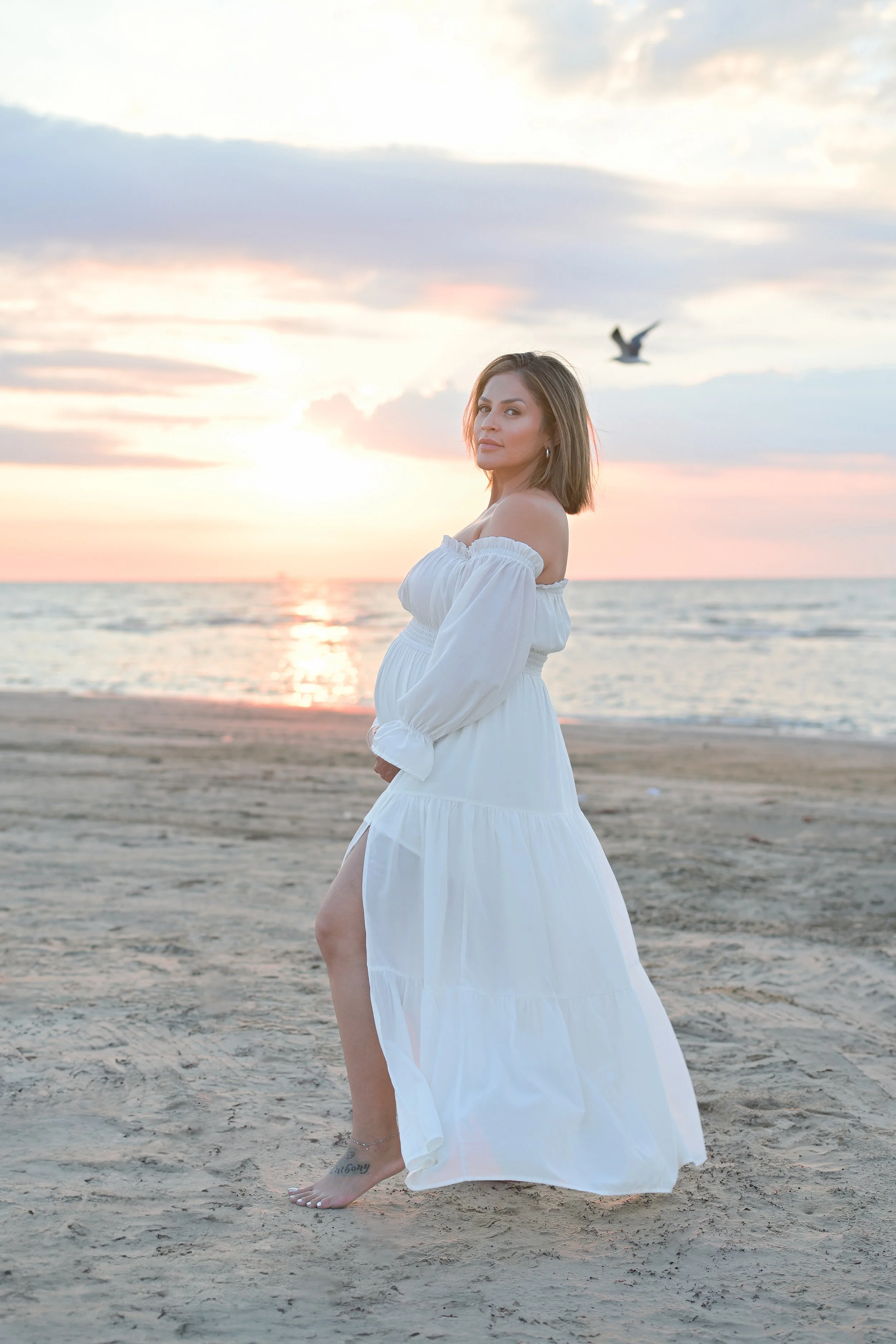 houston mom maternity photos on the beach at sunrise with bird flying in the background