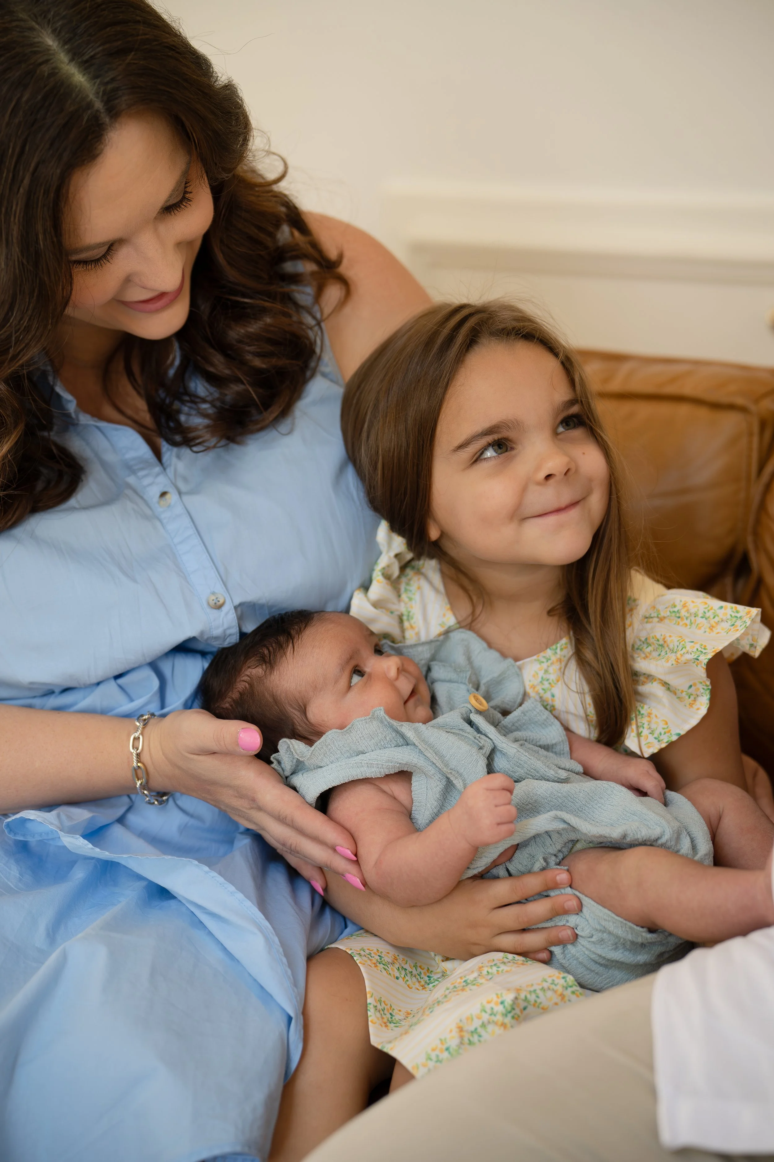 A mom, toddler & newborn cuddling on the couch of their The Woodlands home.