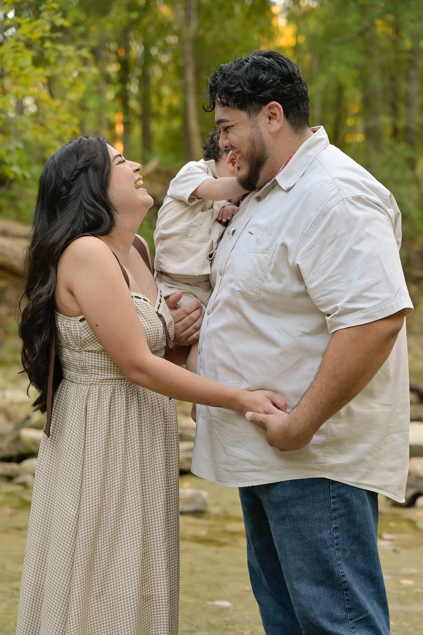 the woodlands mom dad and toddler in nature laughing while hiding child's face
