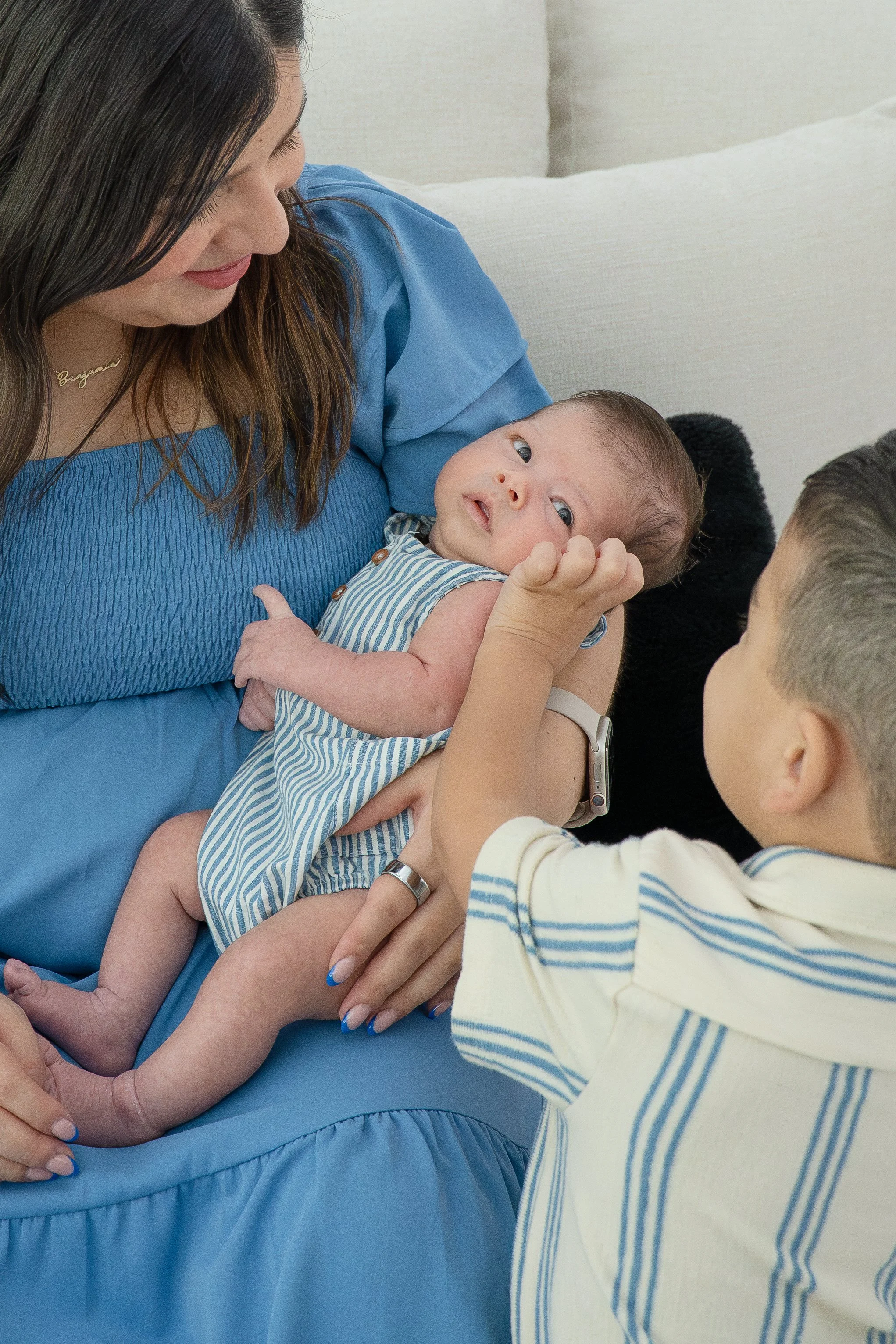 A woman holding a baby while two children reach towards the baby, in their The Woodlands home.
