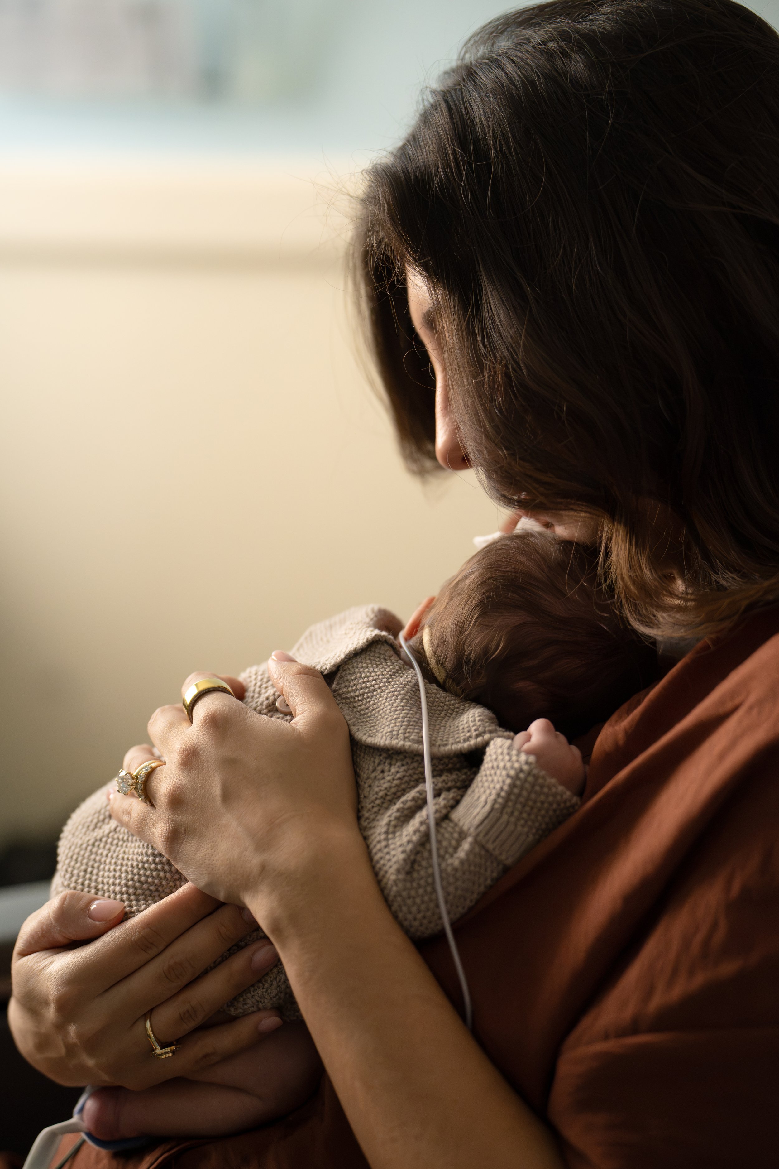 A woman holding and gently kissing a small baby, embracing the baby close to her chest. The woman is wearing multiple rings on her fingers at Houston medical center.