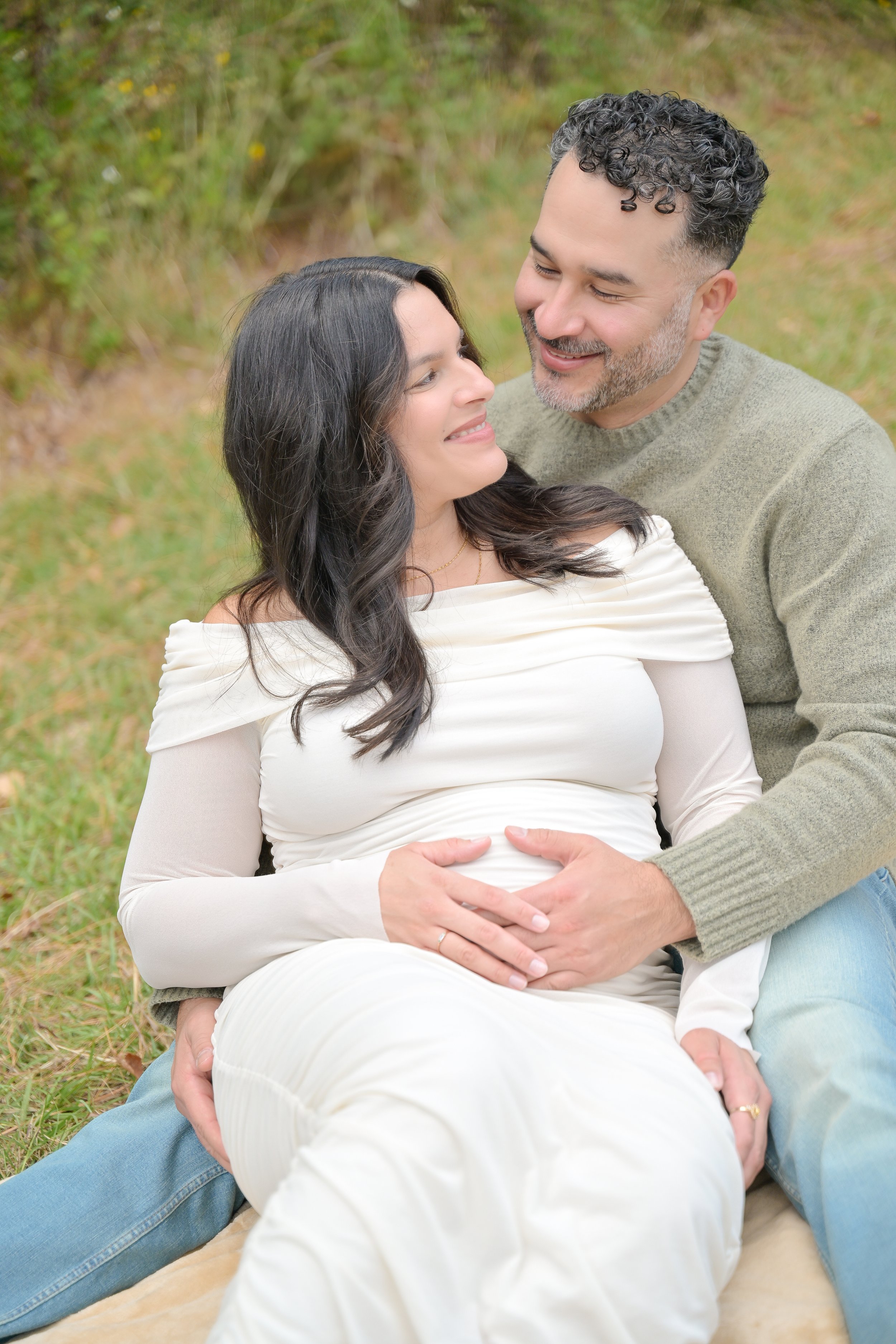 couple embracing holding maternity belly in the houston heights nature park smiling togther