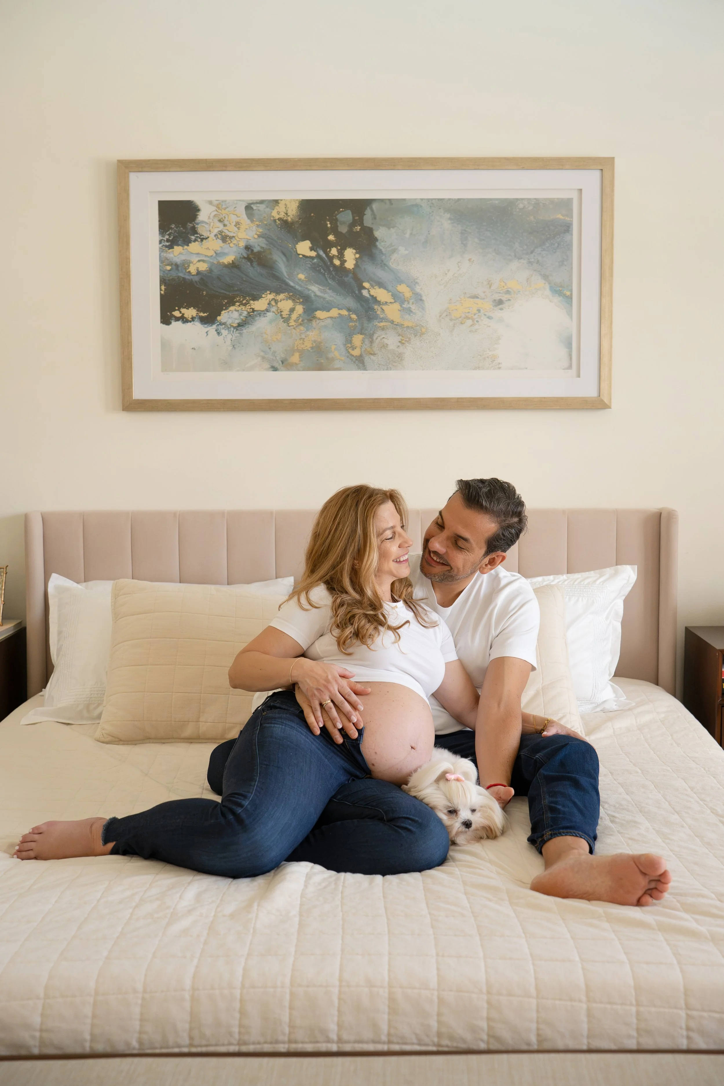 houston heights couple cuddling in bed holding maternity belly during photos at home