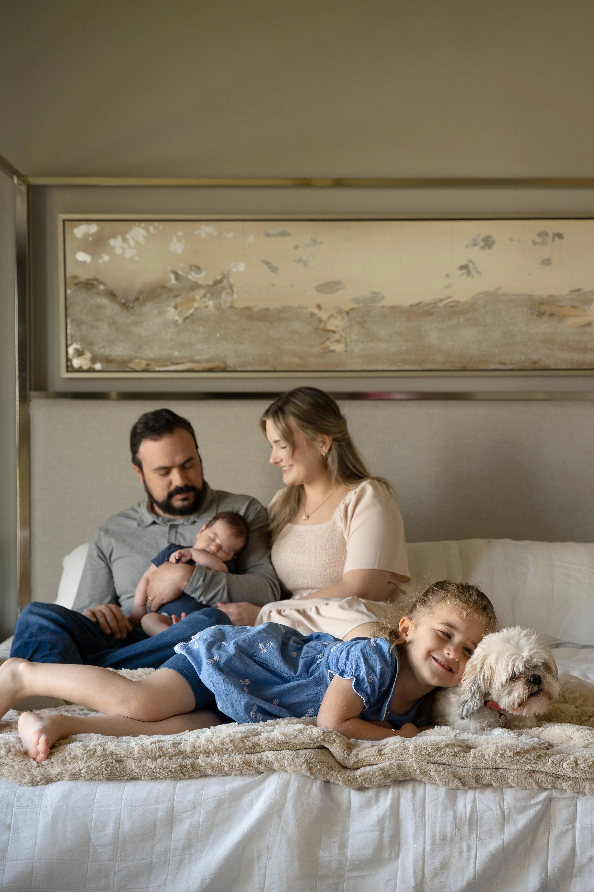 houston family cuddling on the bed with baby and dog