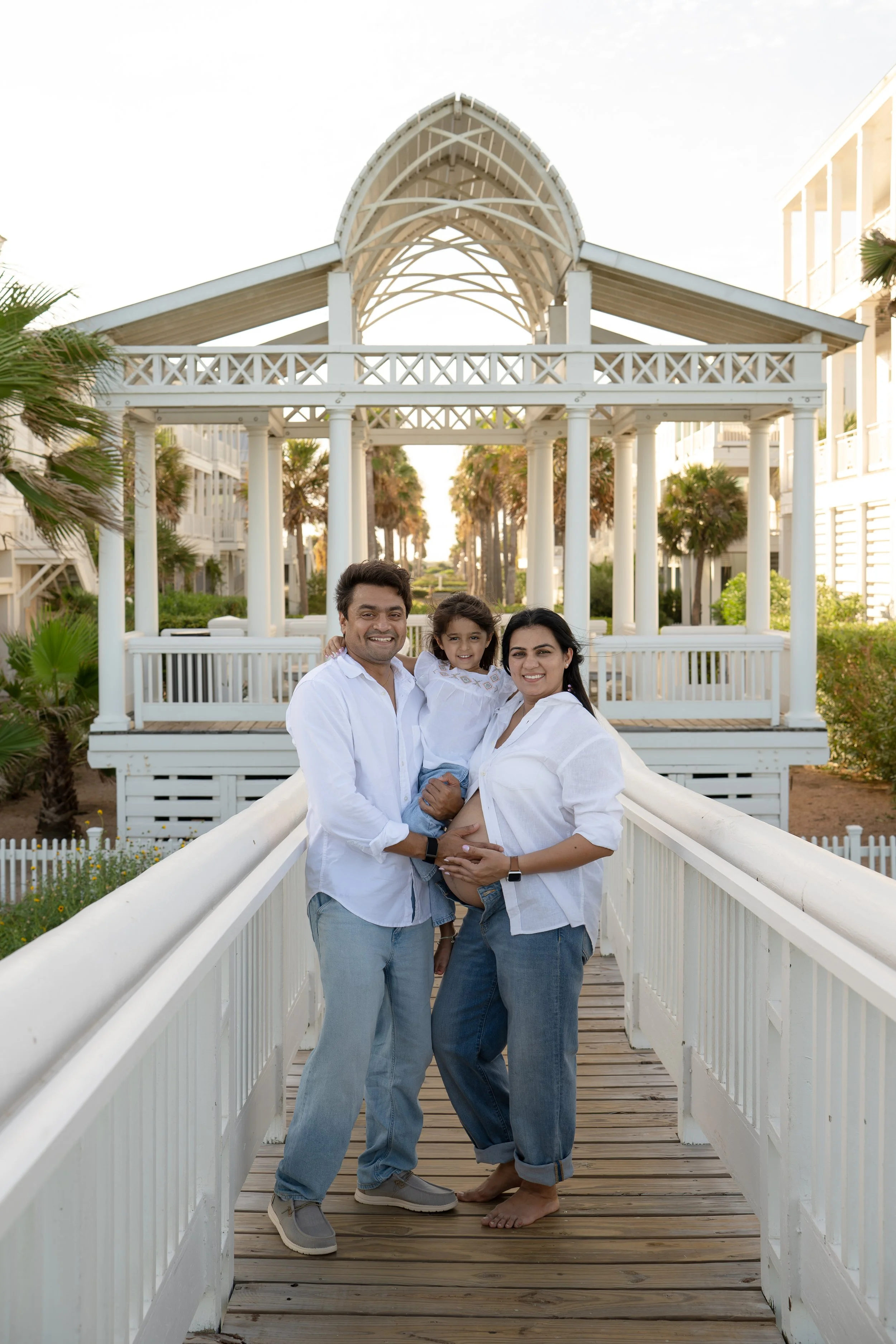 maternity family photos on the beach in front of white bridge beach town all smiles