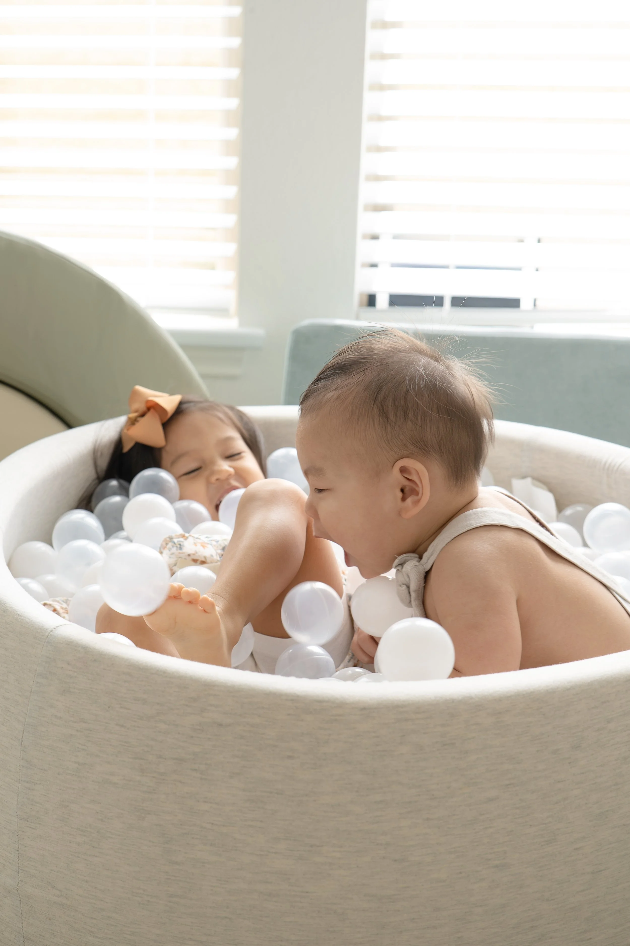 two houston katy-area toddlers engaged in play with plastic balls at home
