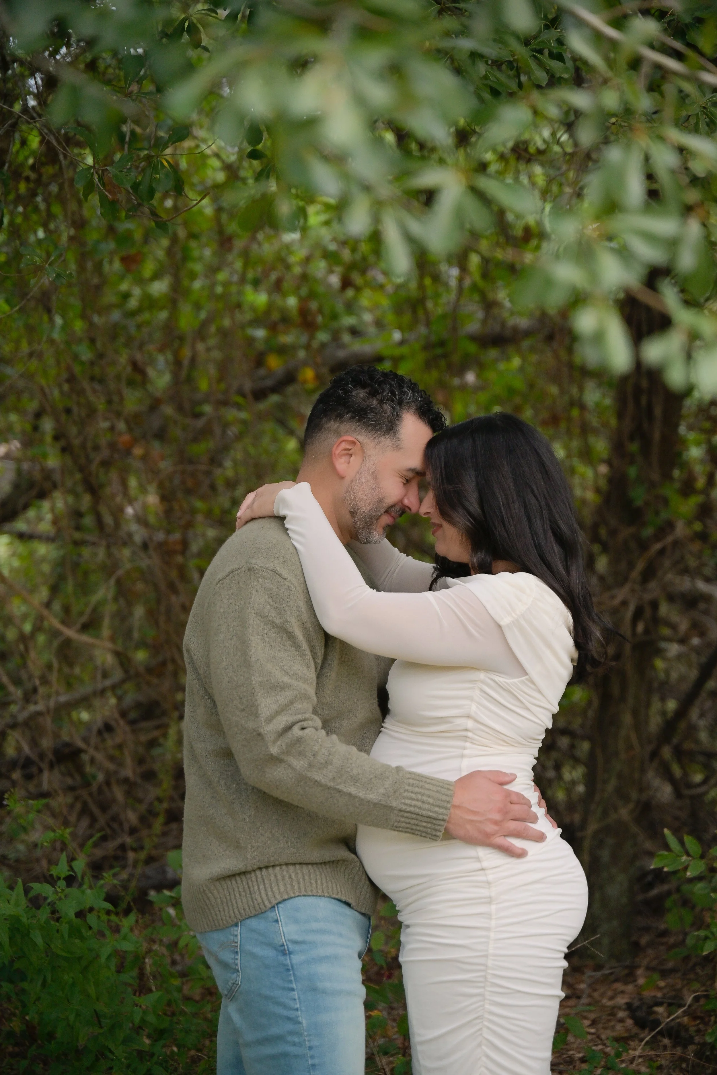 couple embracing holding maternity belly in the houston heights nature park