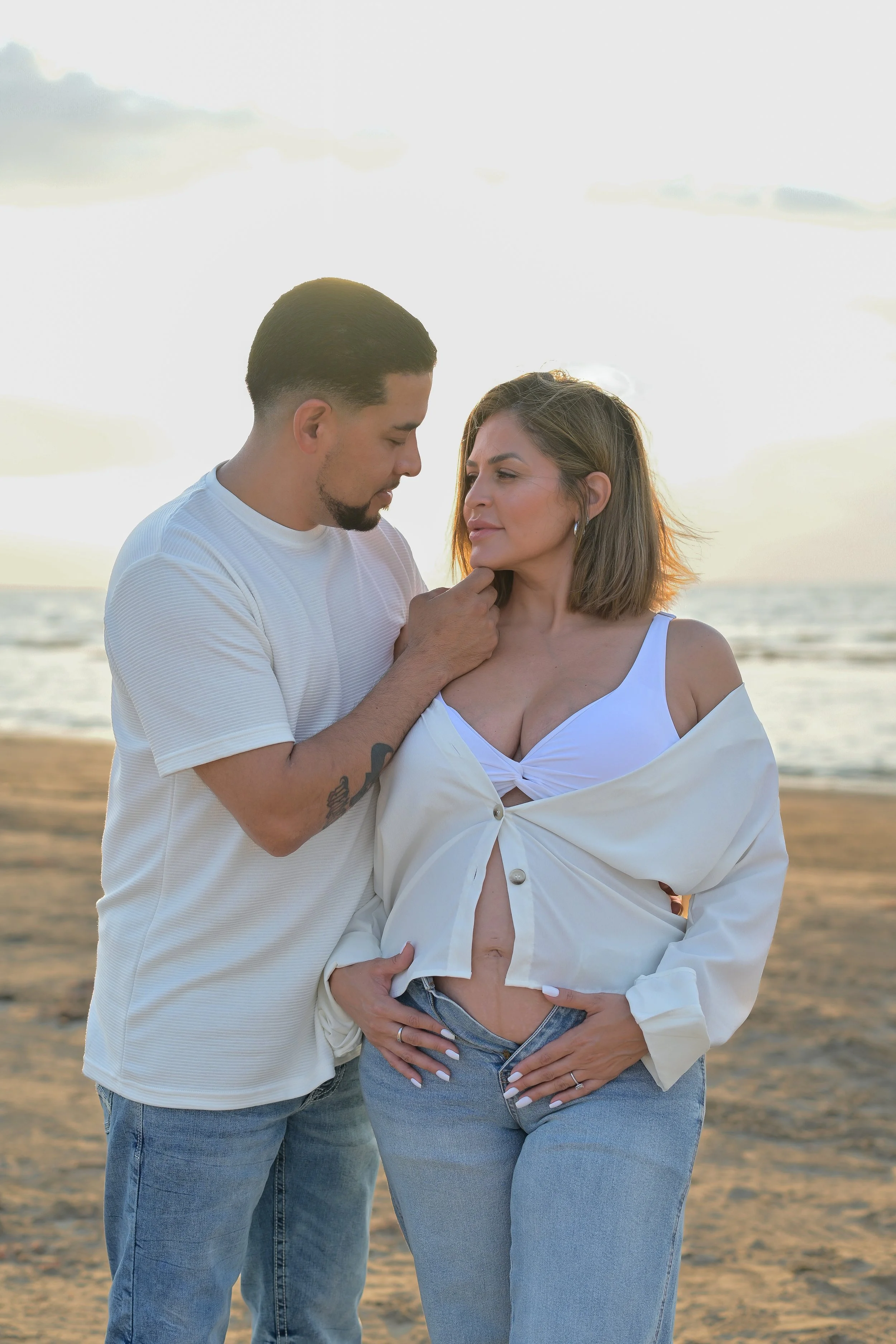 houston couple embracing while pregnant belly on display at the beach