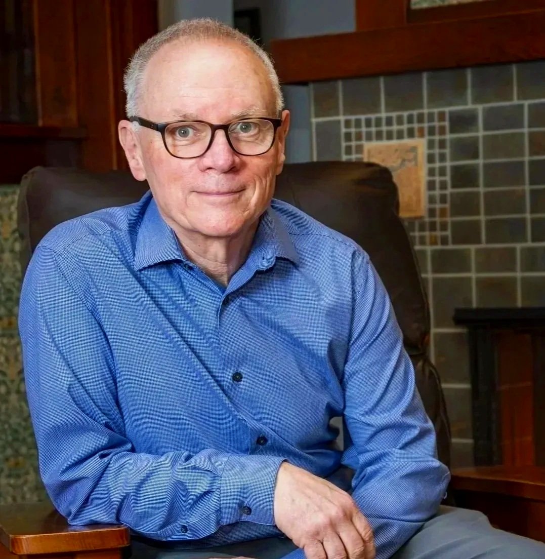 David Womack in a blue shirt sitting in a chair indoors.
