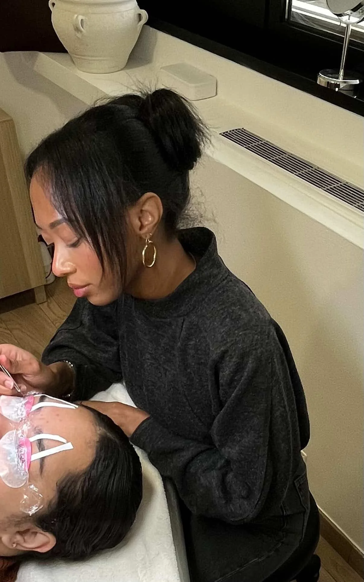 Ramara Beauty esthéticienne extensions de cils en prestation extension de cils à Lyon sur une femme brune. Femme elegante. Boucle d'oreils couleur or vêtements noir. Vase blanc aesthetic.jpg