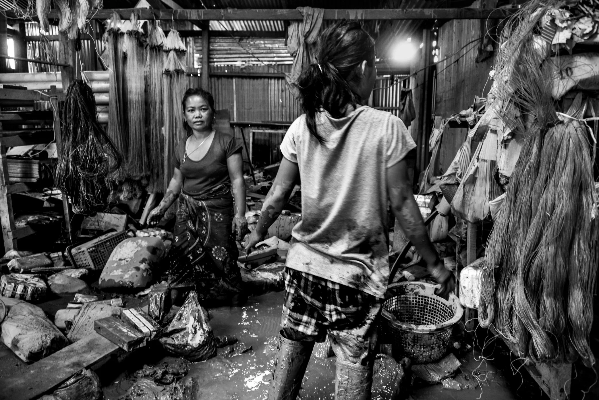 Khok Kong Village, Attapeu, Laos - Shop owners stand inside their flooded store after the Xe Pian dam collapse. Khok Kong was one of seven villages damaged by the disaster, where water and mud entered homes, shops, and storage rooms, destroying goods